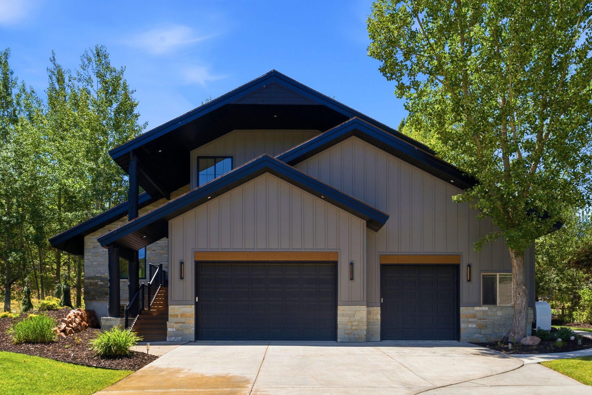 Contemporary exterior featuring vertical siding, stone accents, and a multi-gabled roofline