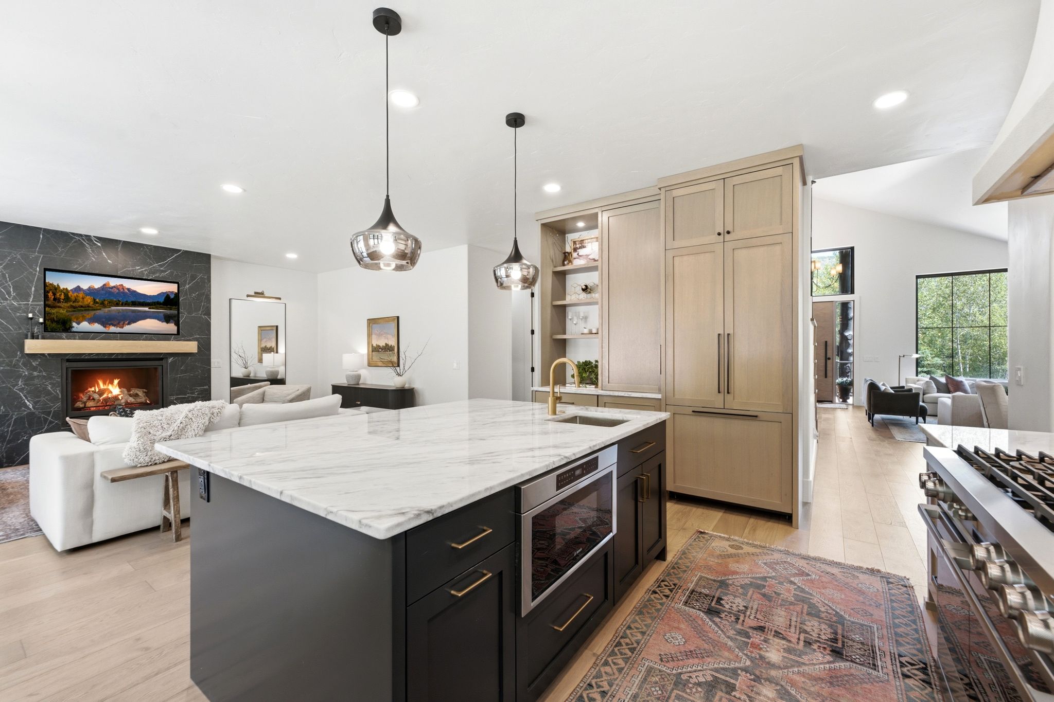 Open-concept living space featuring a central kitchen island with a built-in microwave, integrated full-height refrigerator, and a gas range