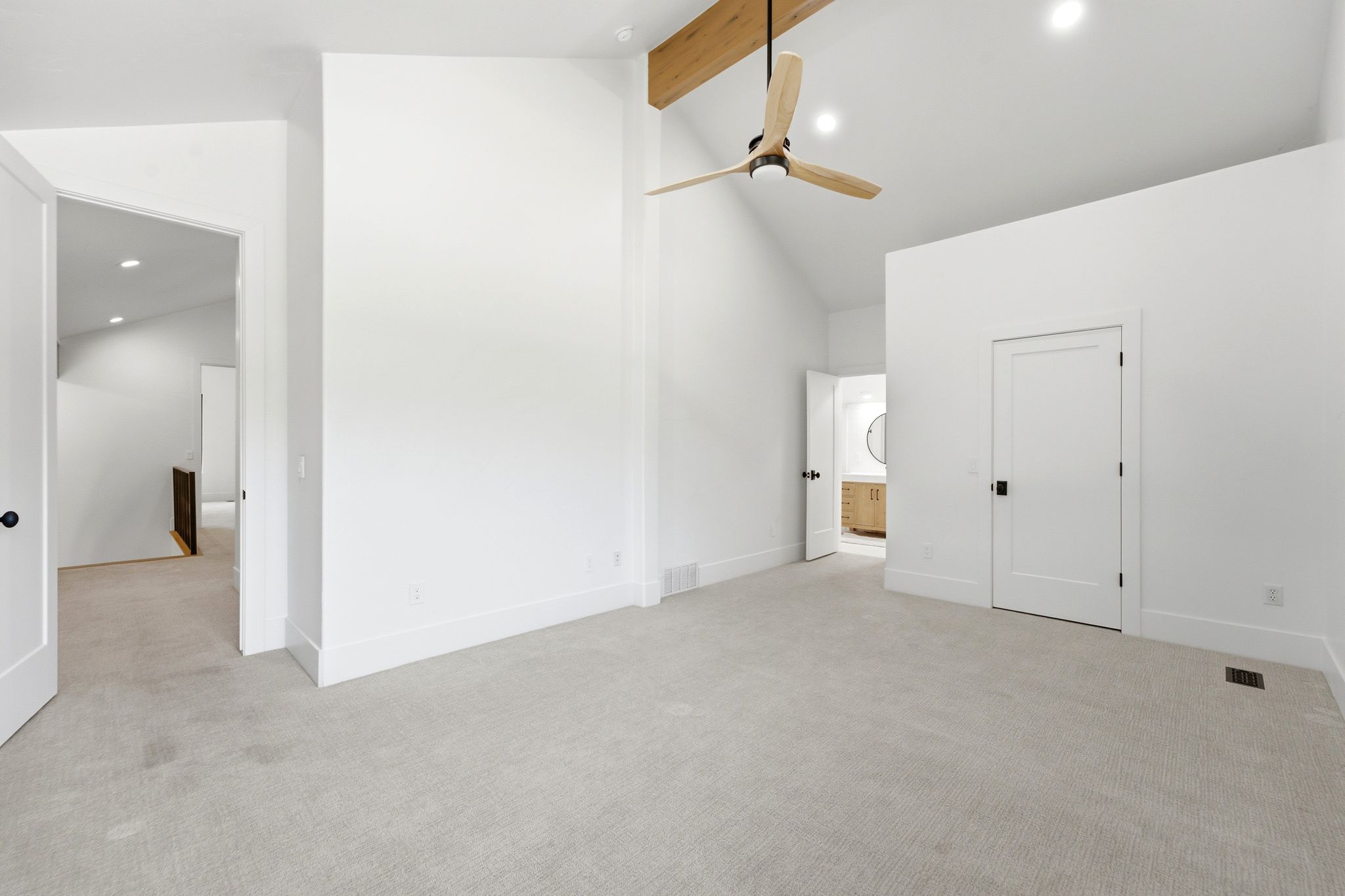 Spacious room featuring vaulted ceilings with an exposed wood beam, a contemporary ceiling fan, and recessed lighting