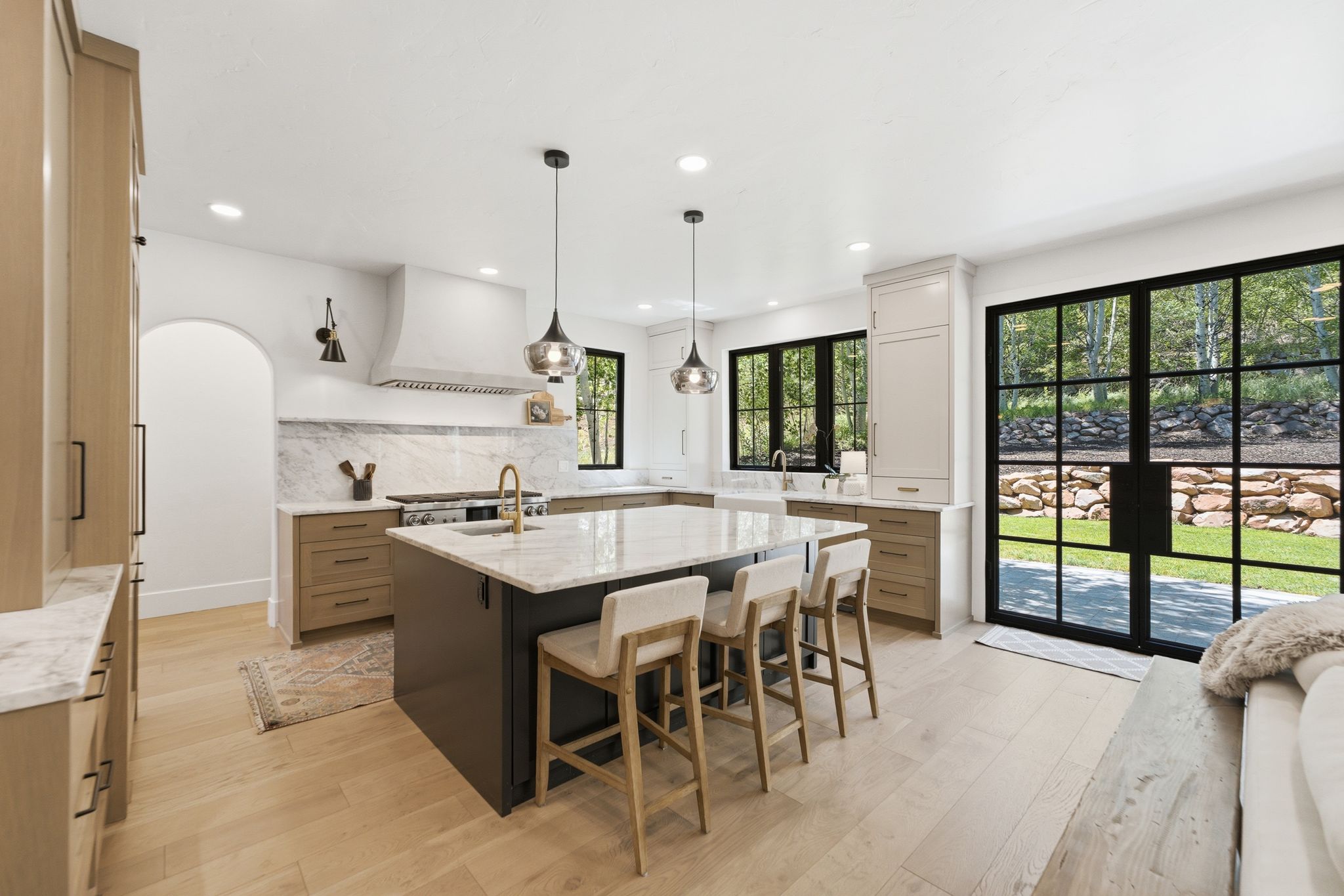 Well-appointed kitchen featuring a large central island with seating, light wood-finish flooring, and a marble backsplash