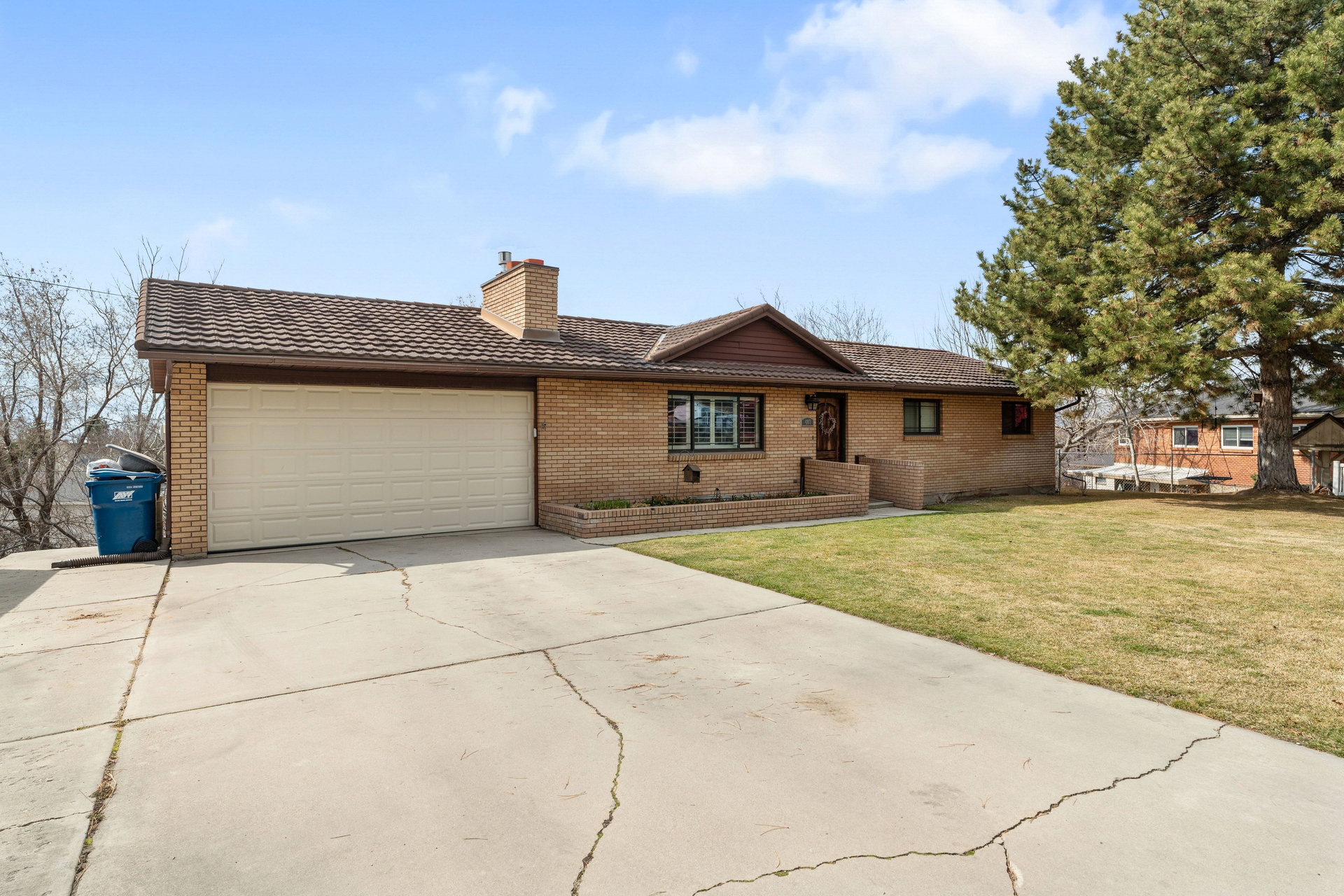 Brick exterior home with an attached two-car garage, featuring a shingled roof and a front lawn