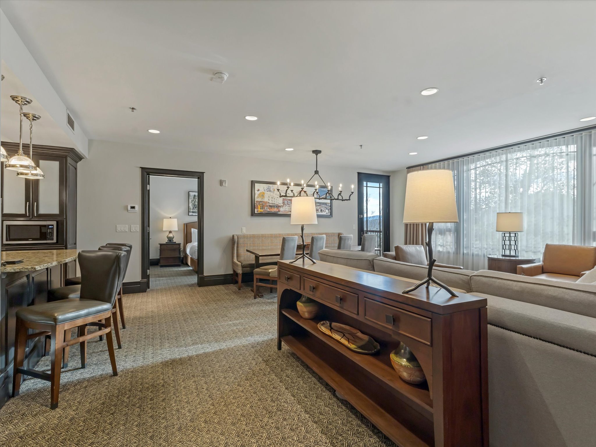 Spacious open-concept living area featuring wall-to-wall carpeting, recessed lighting, and large windows with sheer privacy curtains