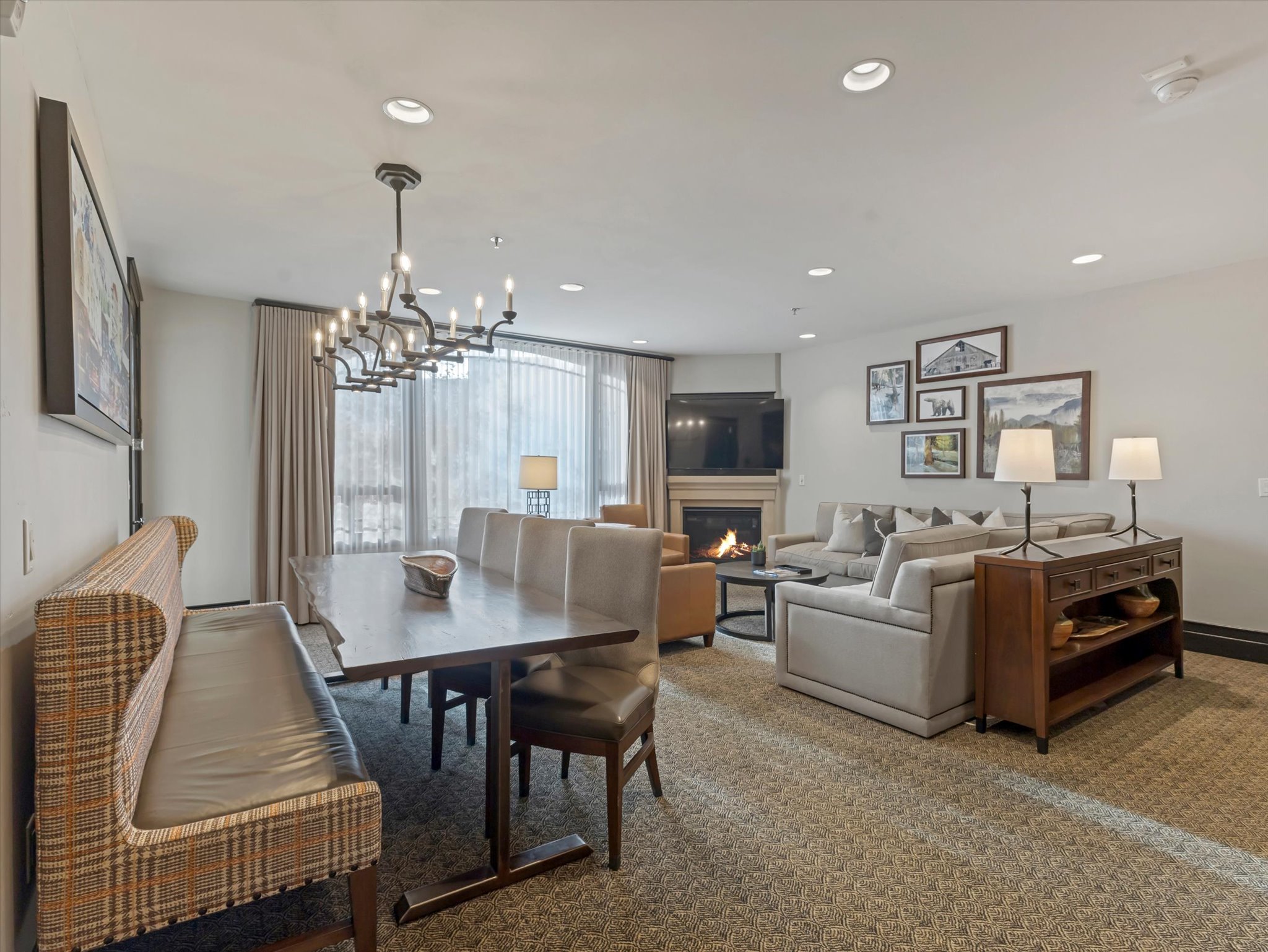 Open-concept living area featuring a fireplace, recessed lighting, expansive windows with drapes, a multi-light chandelier, and patterned carpeting