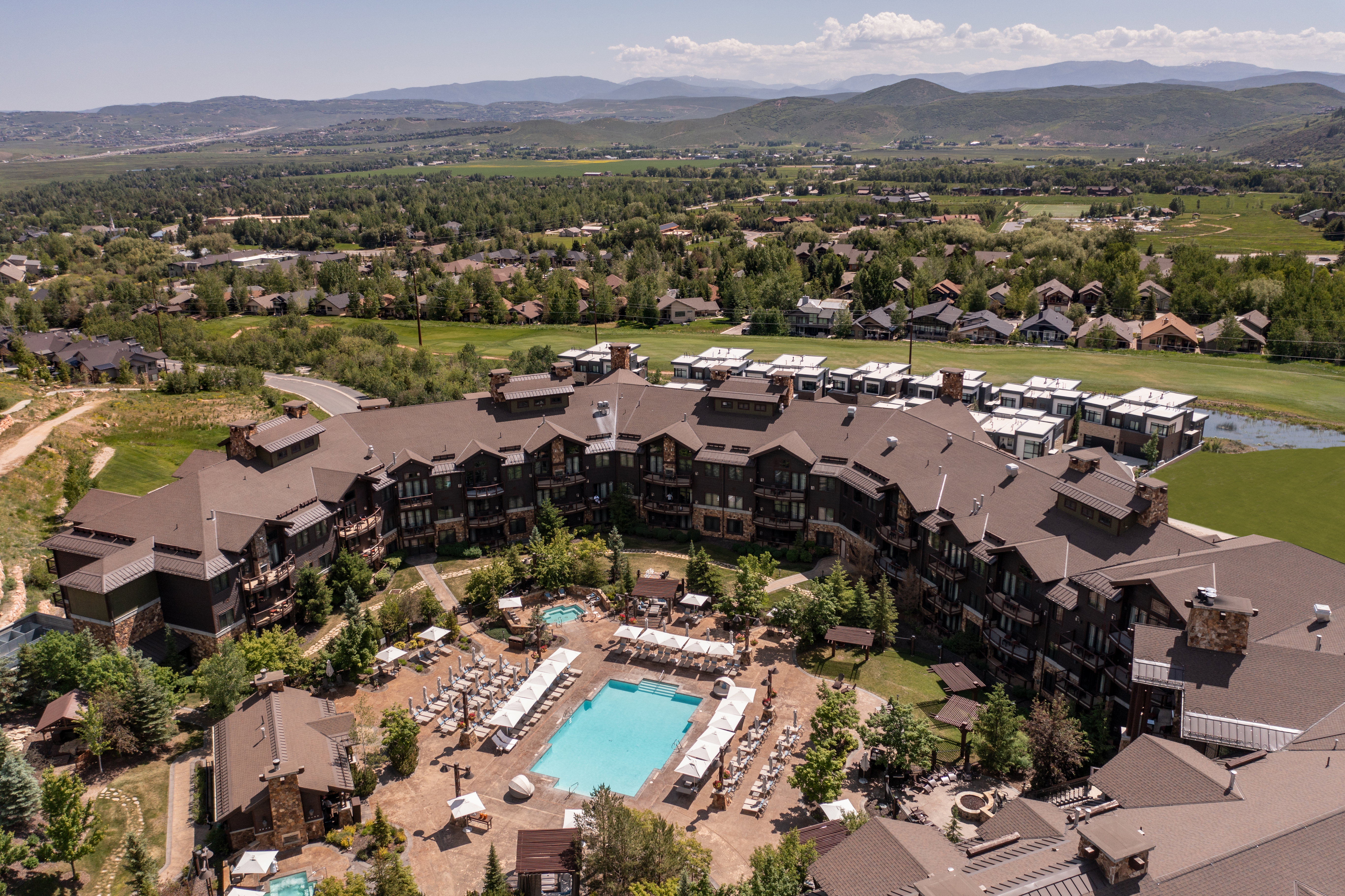 Expansive resort-style property featuring a large outdoor swimming pool, multiple hot tubs, and established landscaping