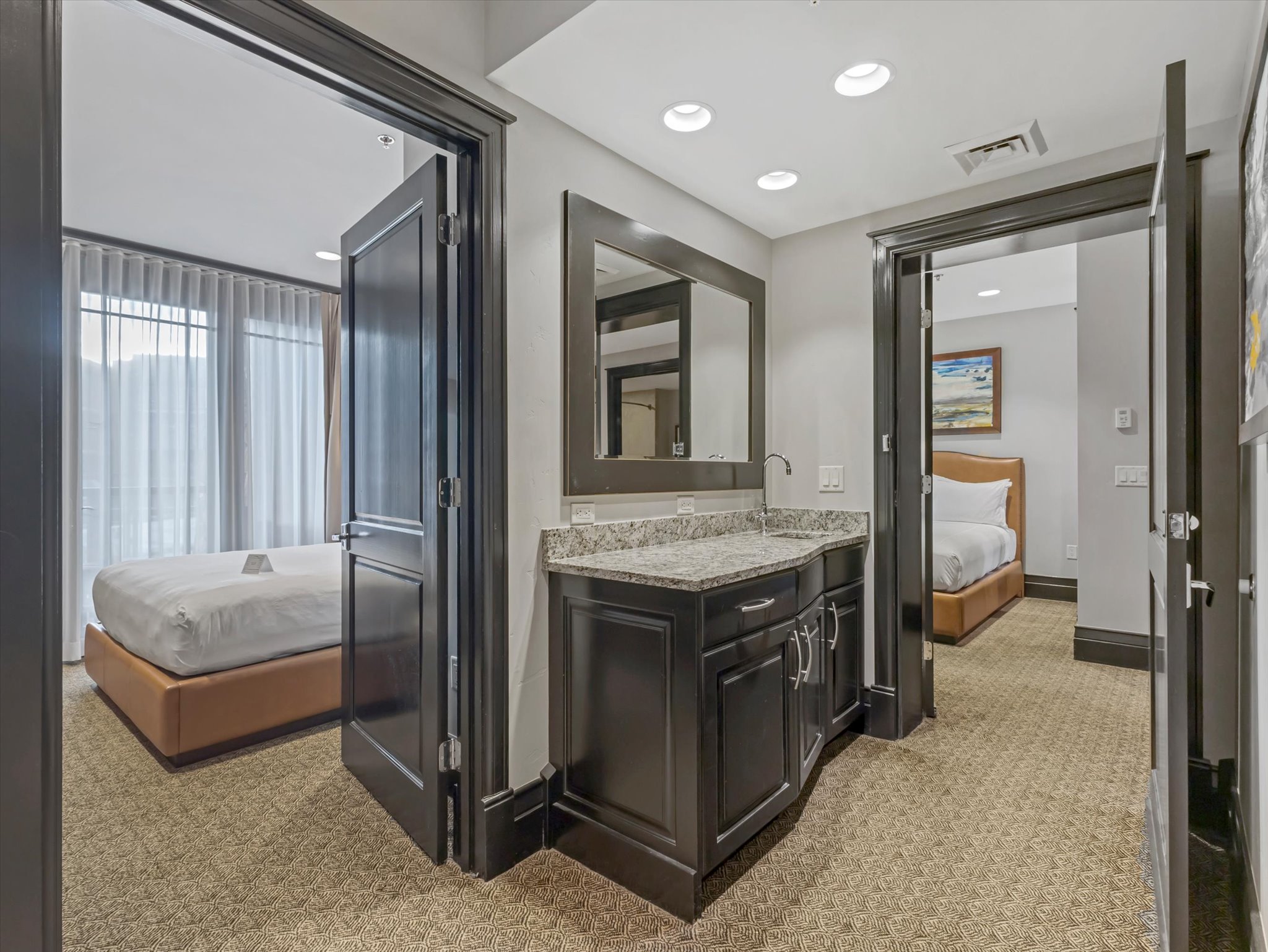 Compact wet bar featuring a speckled countertop, undermount sink, and dark wood cabinetry