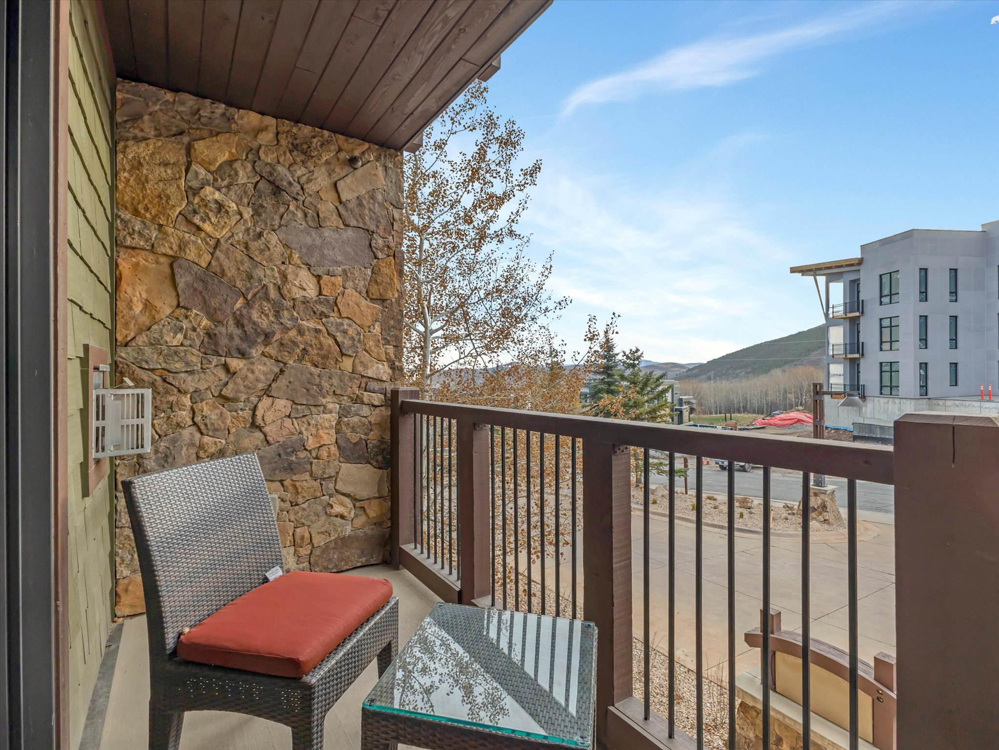 Private balcony featuring natural stone wall accents and wood-finish railing