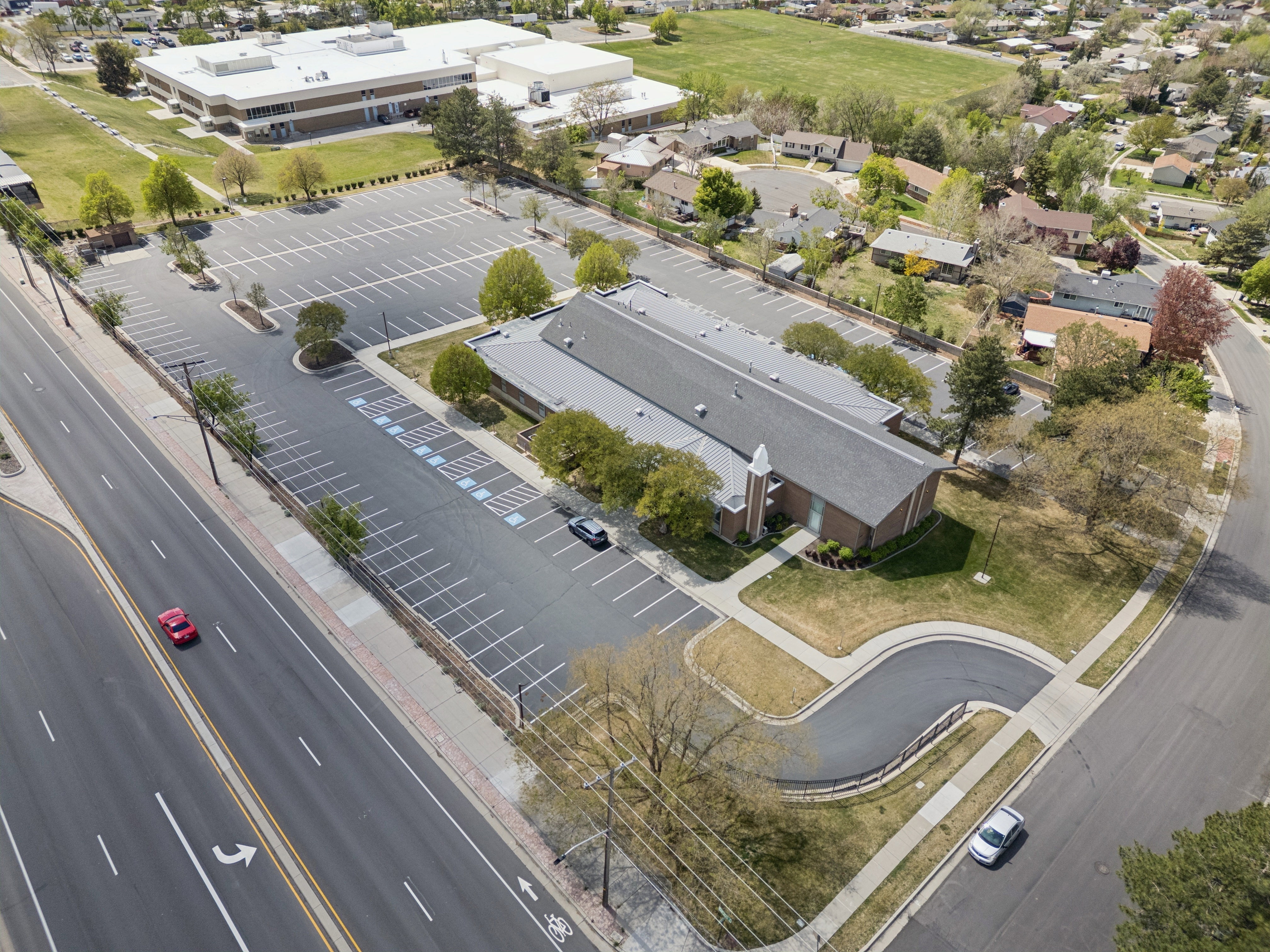 Large parking lot with marked spaces, bordered by a main road and residential streets