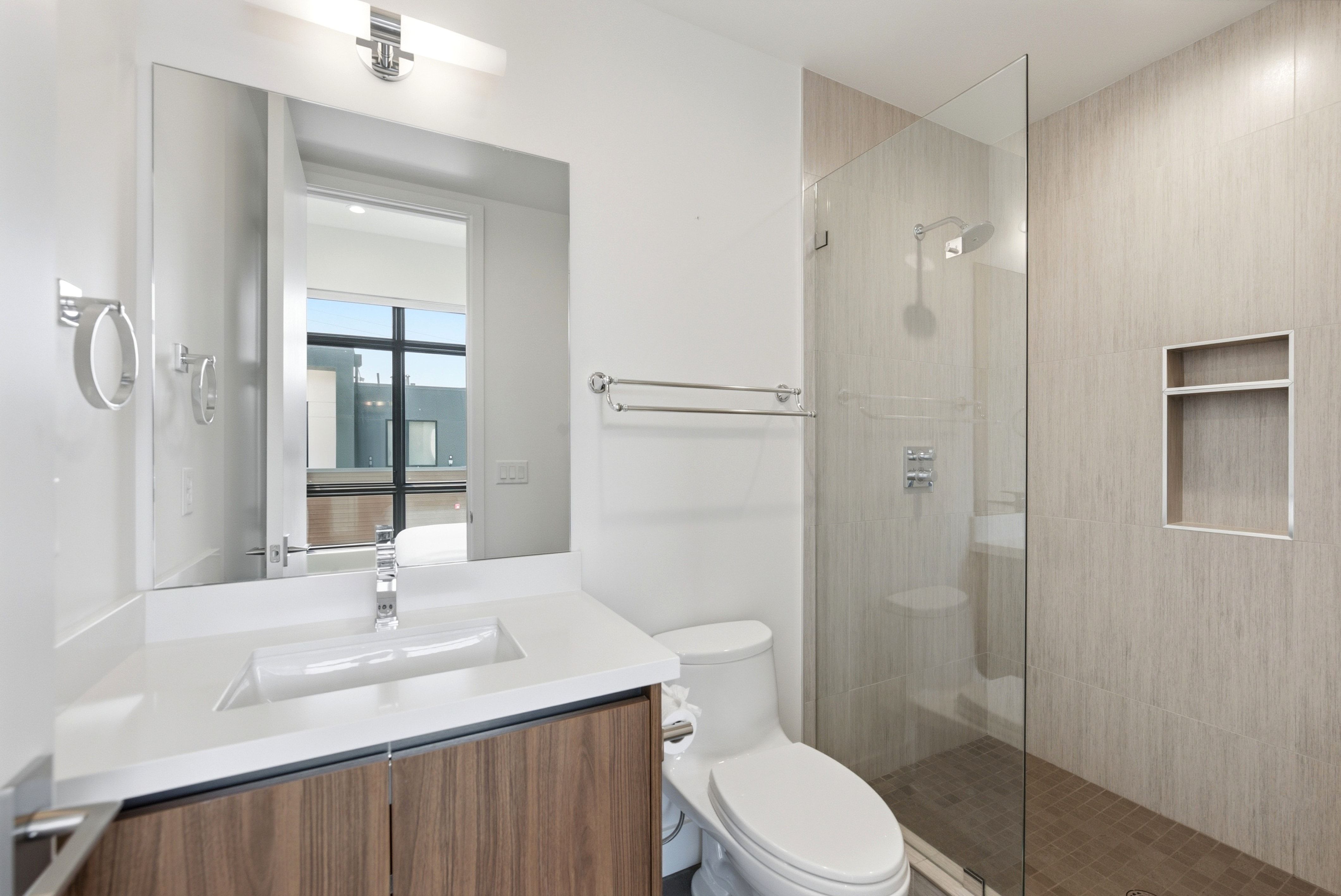 Modern bathroom featuring a single vanity with wood-finish cabinetry and a white countertop