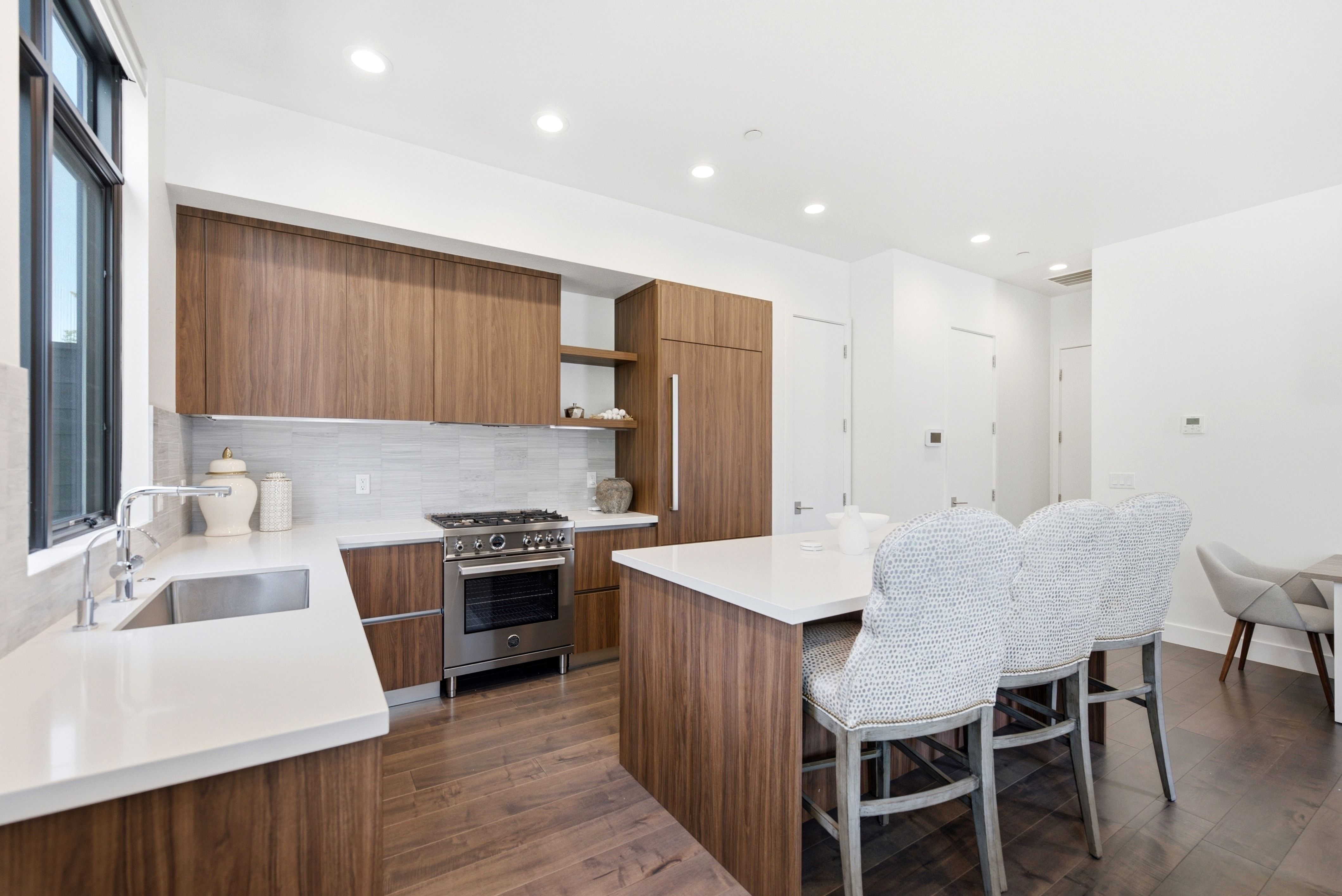 Modern kitchen featuring wood-finish cabinetry, white countertops, and stainless steel appliances