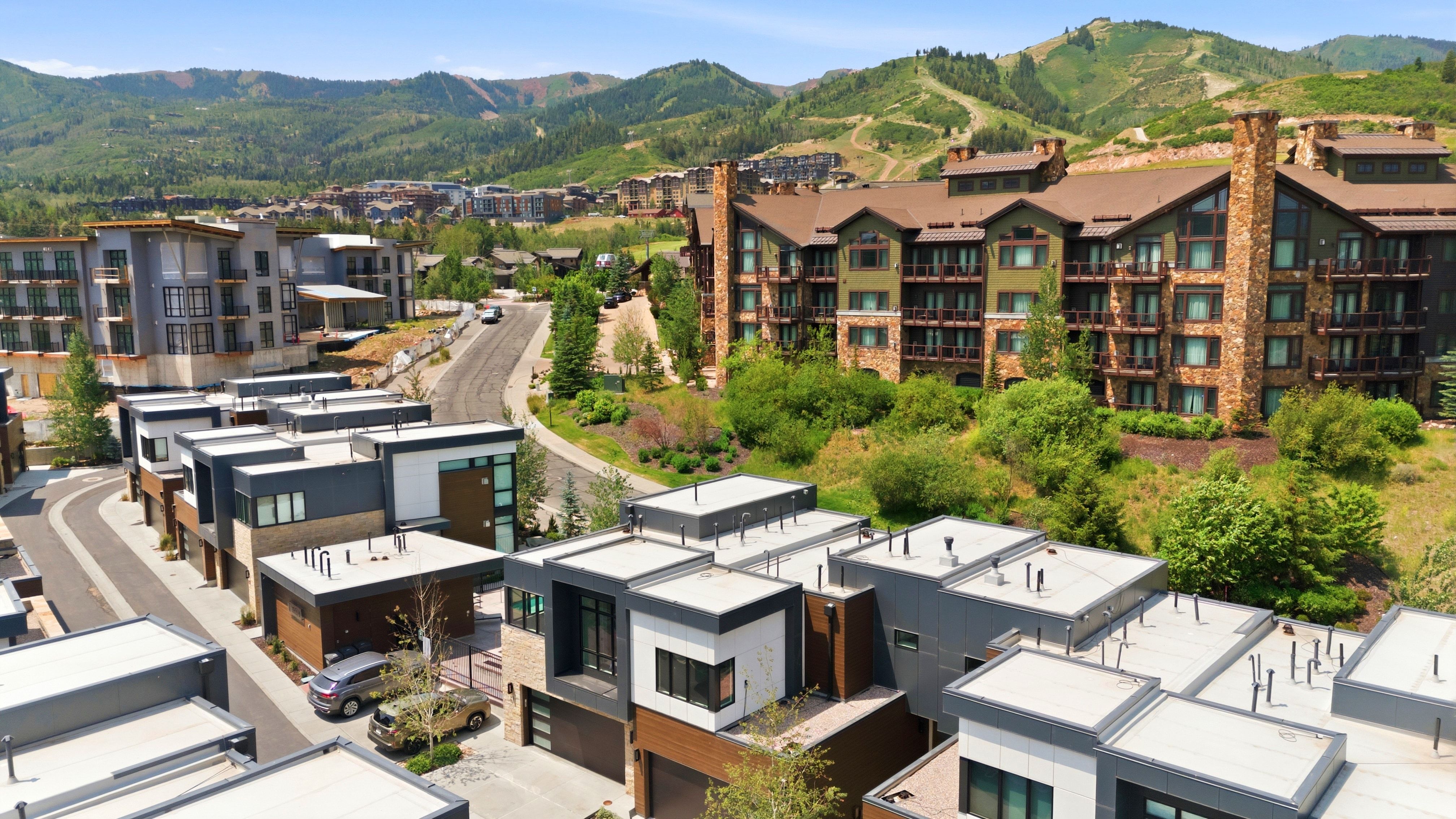 Modern townhomes featuring a contemporary architectural design, flat rooflines, and a mix of exterior materials including light-colored siding, dark panels, and stone accents