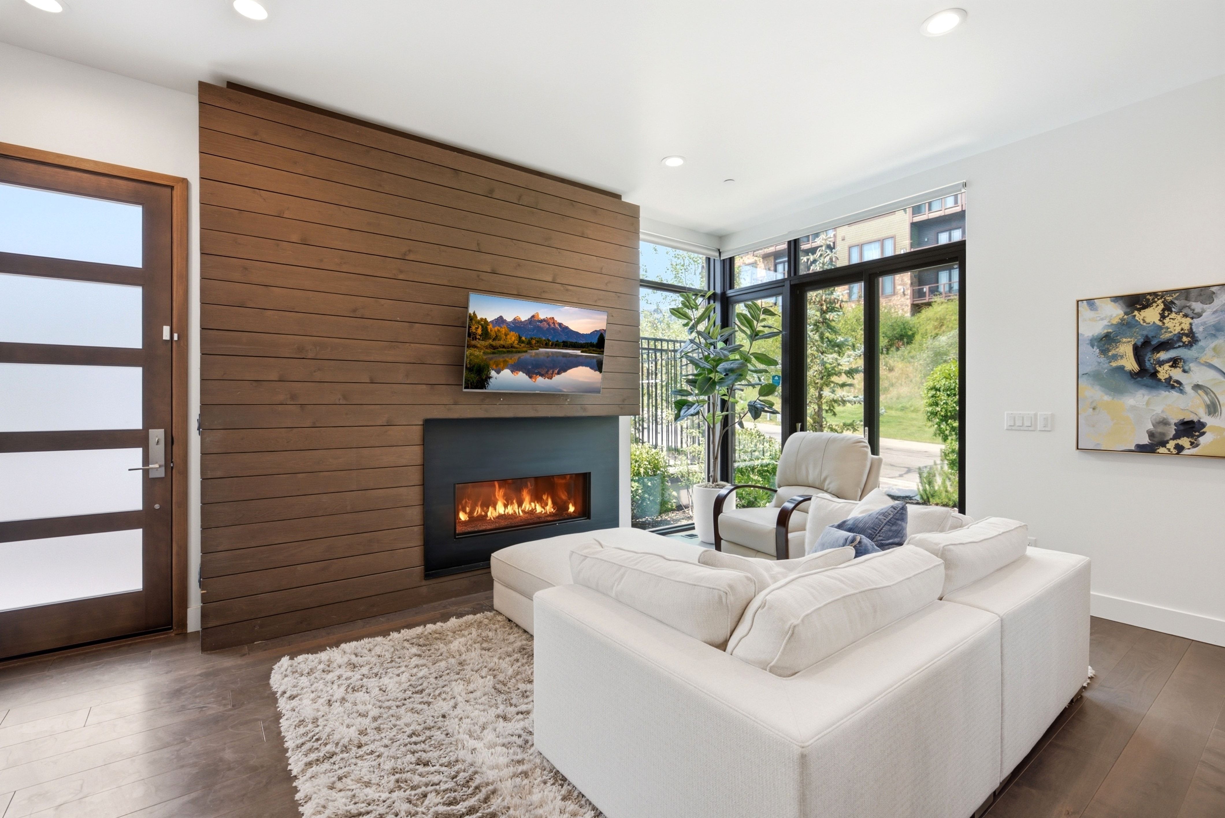 Living area featuring a floor-to-ceiling wood-panel accent wall with an integrated modern fireplace