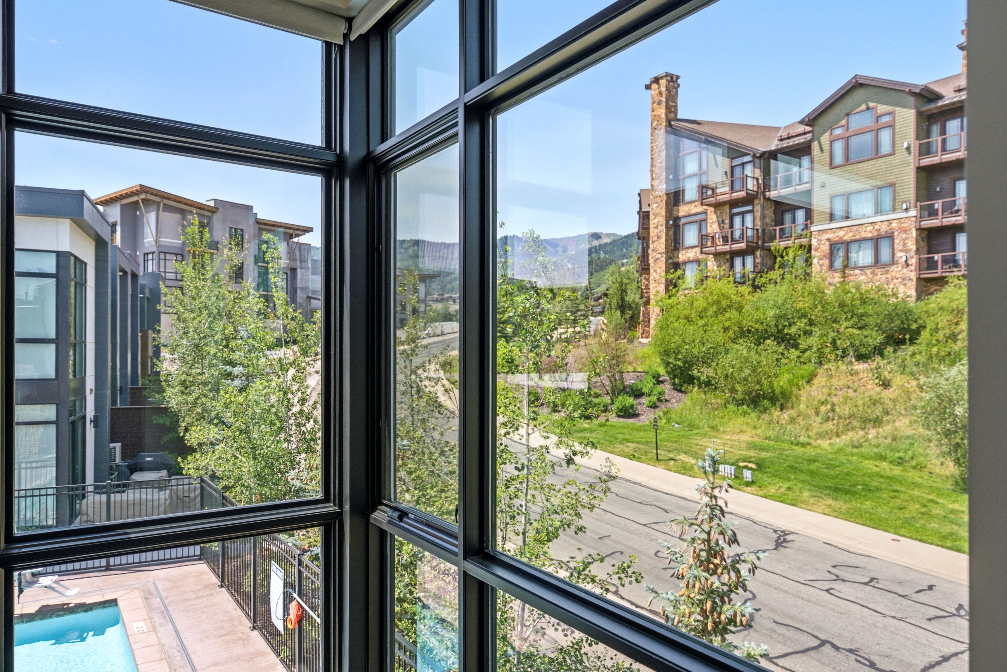 Floor-to-ceiling windows with dark frames, showcasing an outdoor swimming pool with surrounding fencing