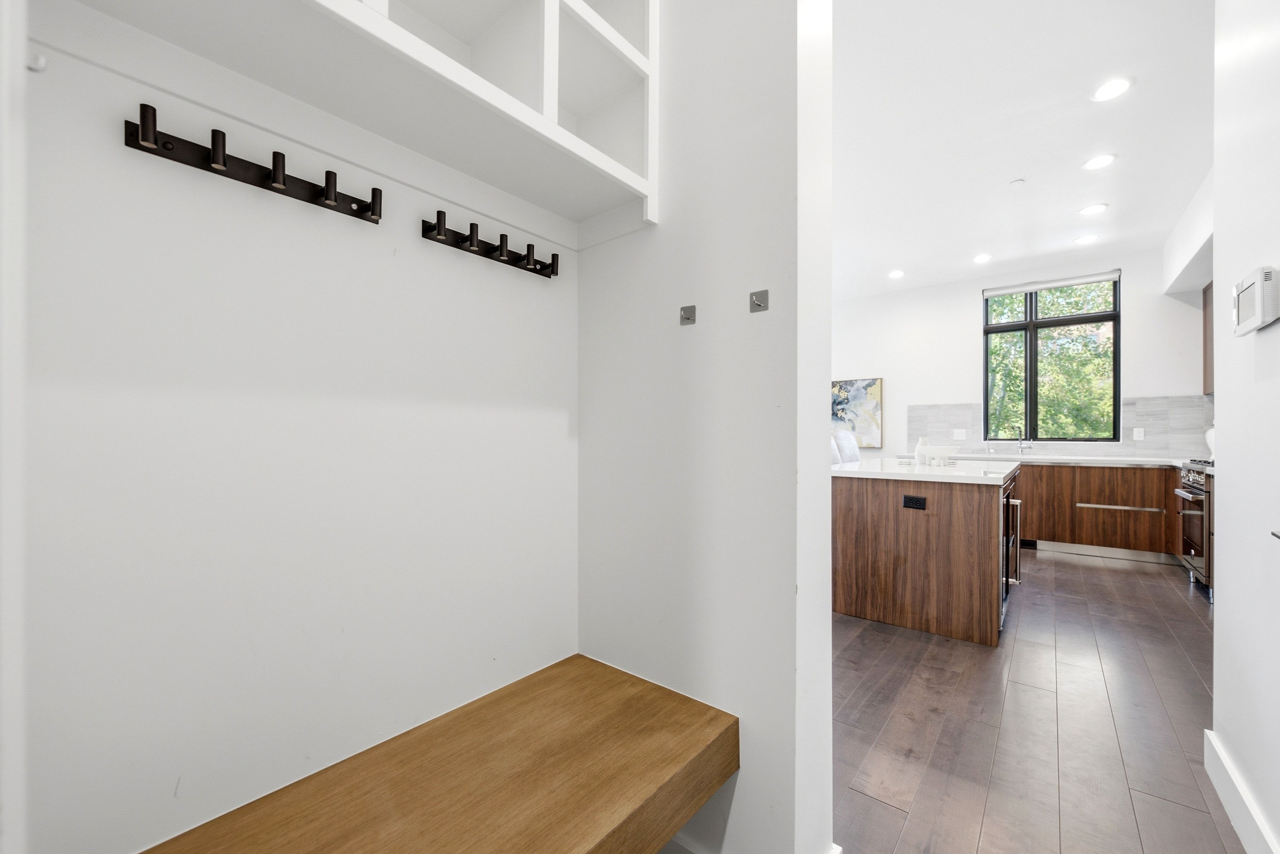 Entryway featuring a built-in bench and overhead shelving with integrated coat hooks