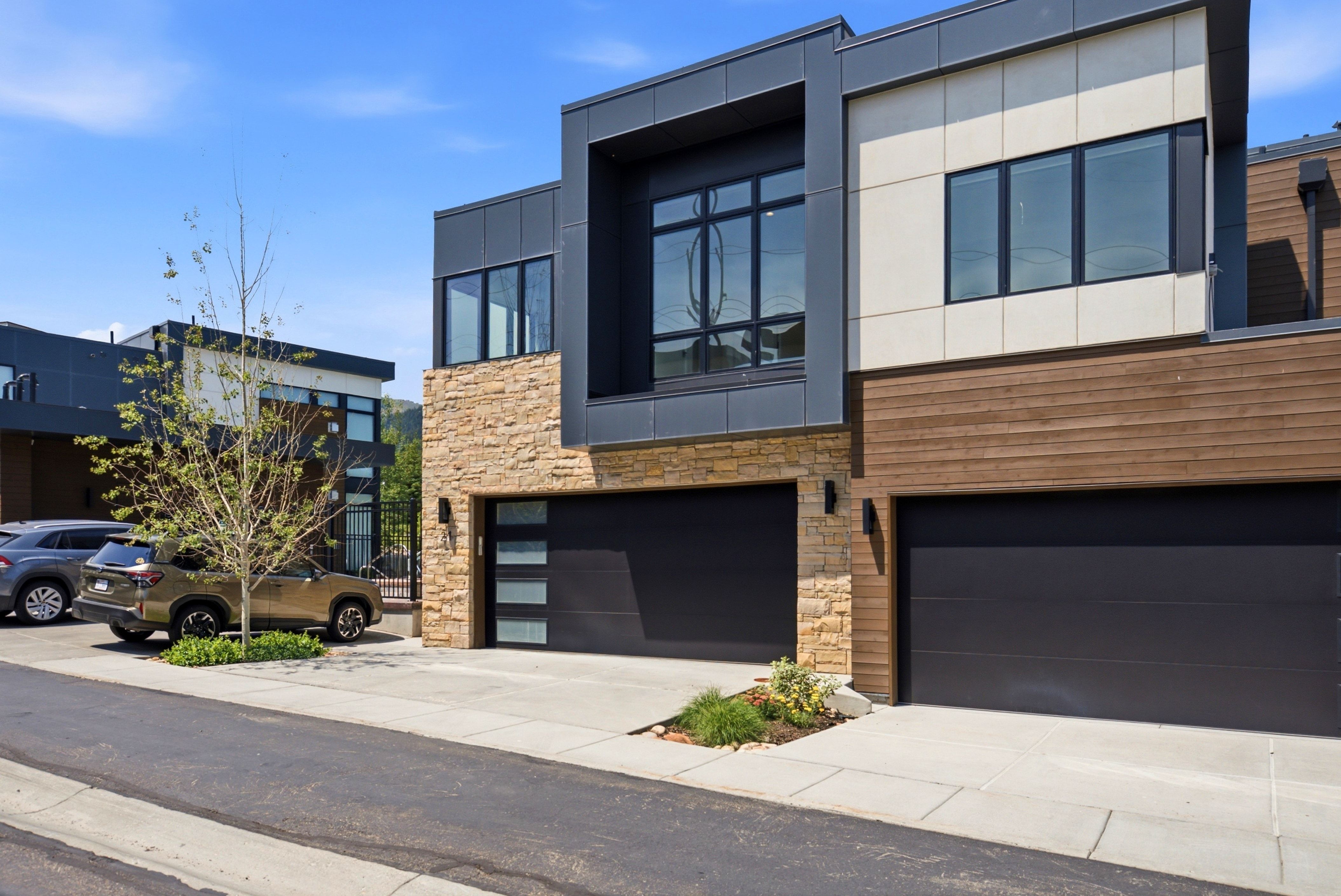 Modern facade featuring a combination of stone, wood-finish siding, and dark paneling