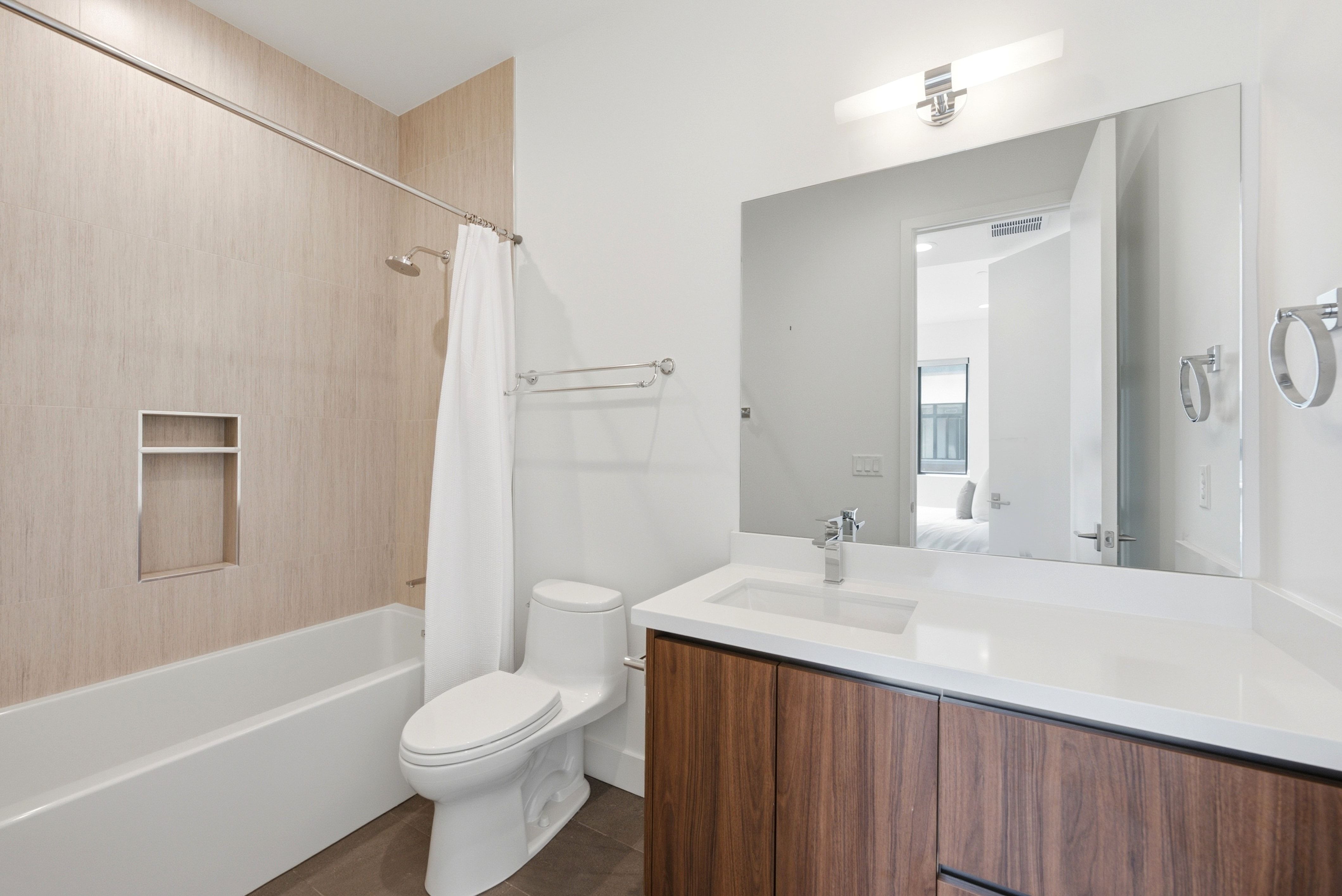 Bathroom featuring a wood-finish vanity with an integrated sink, a white countertop, and a large mirror