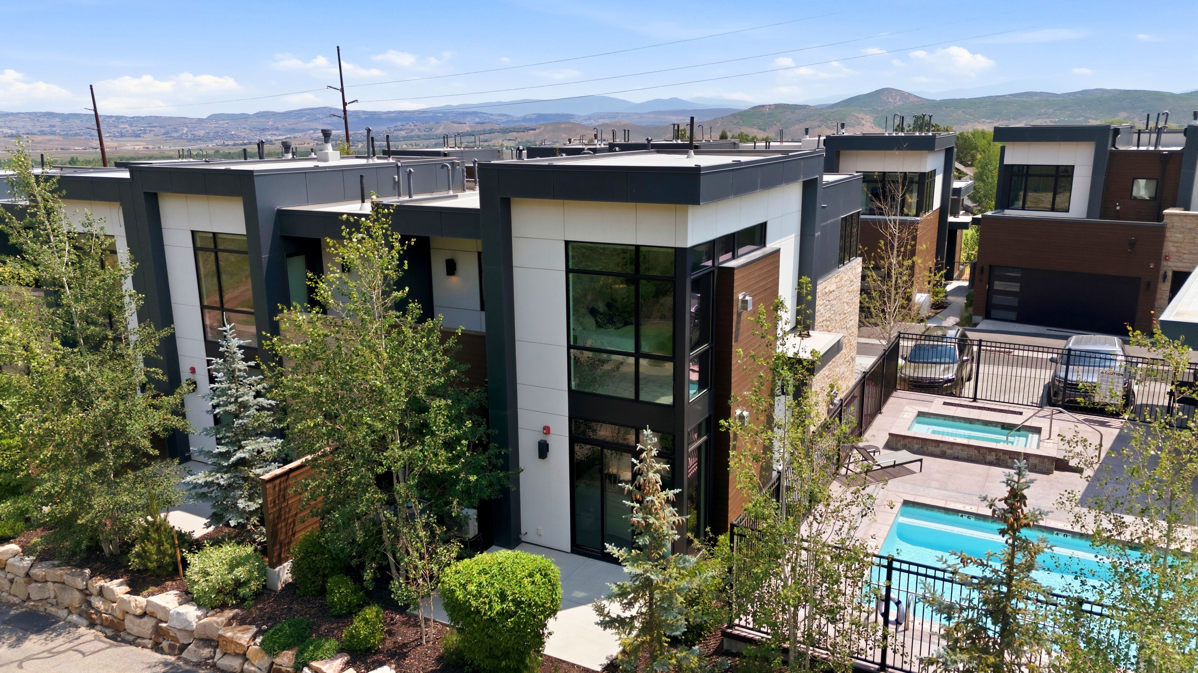 Contemporary multi-story residences featuring dark trim and light paneling, complemented by wood-finish and stone accents
