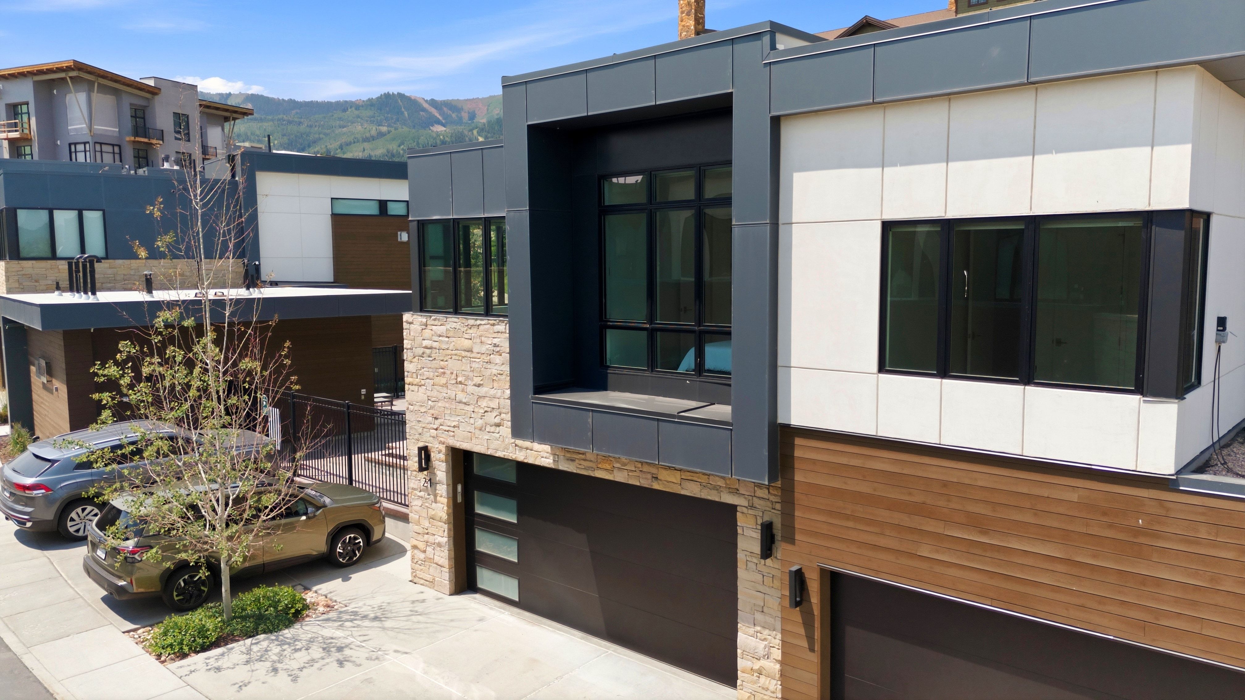 Contemporary exterior featuring stacked stone, horizontal wood-look siding, and large black-framed windows
