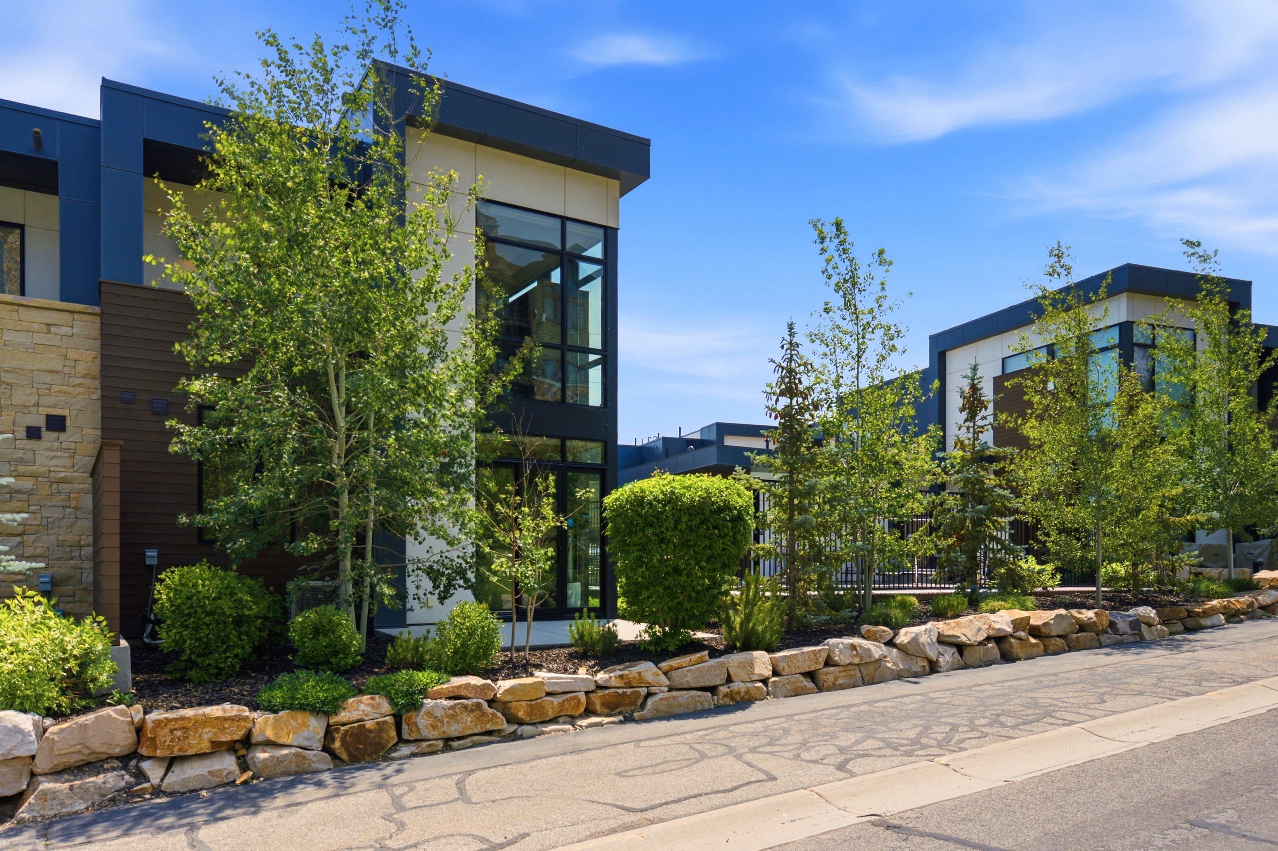 Contemporary exterior featuring a flat roofline, large format windows, and stone veneer accents