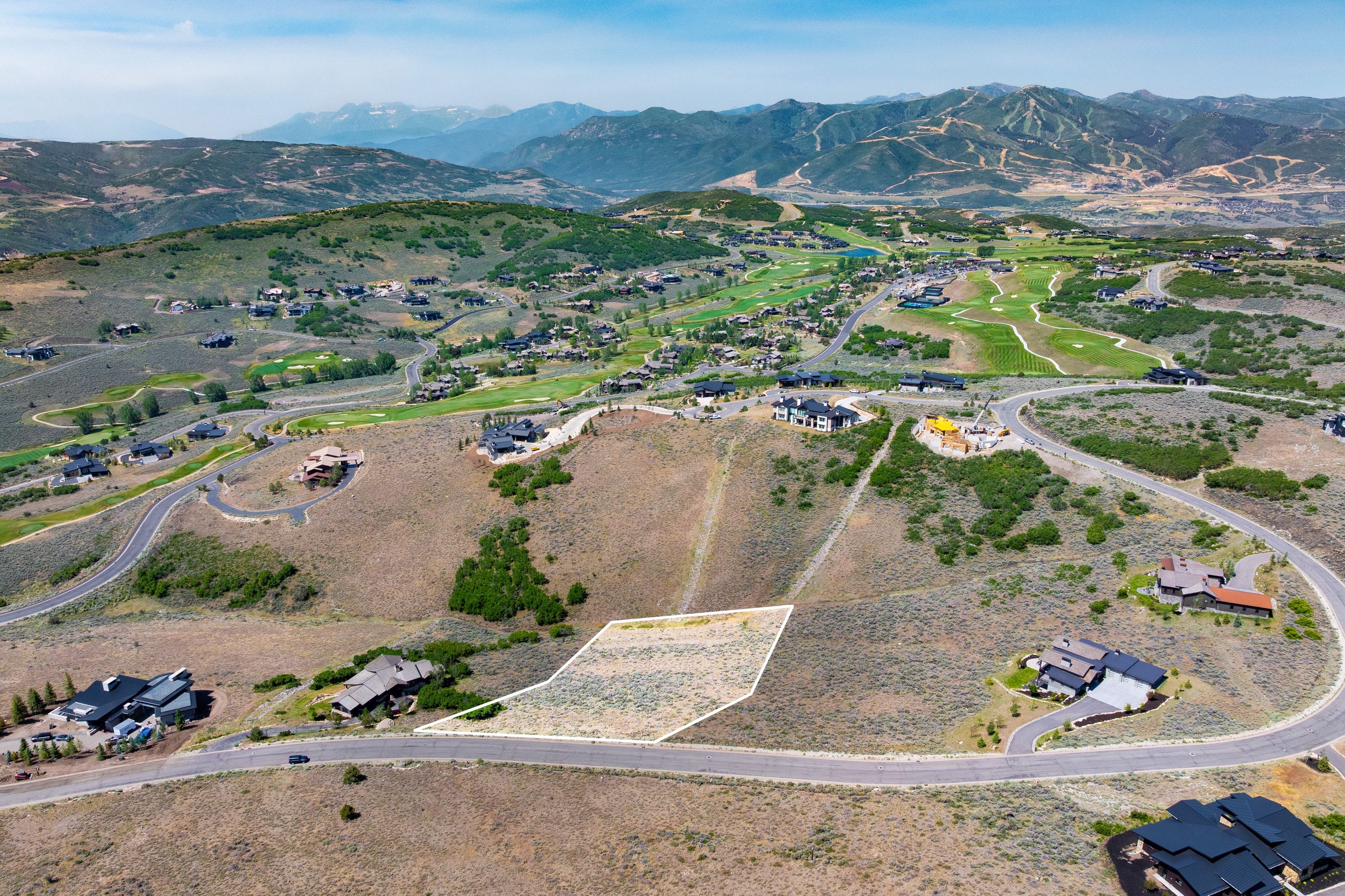 Expansive hillside parcel featuring a mountain backdrop, a paved road frontage, and surrounding residential properties