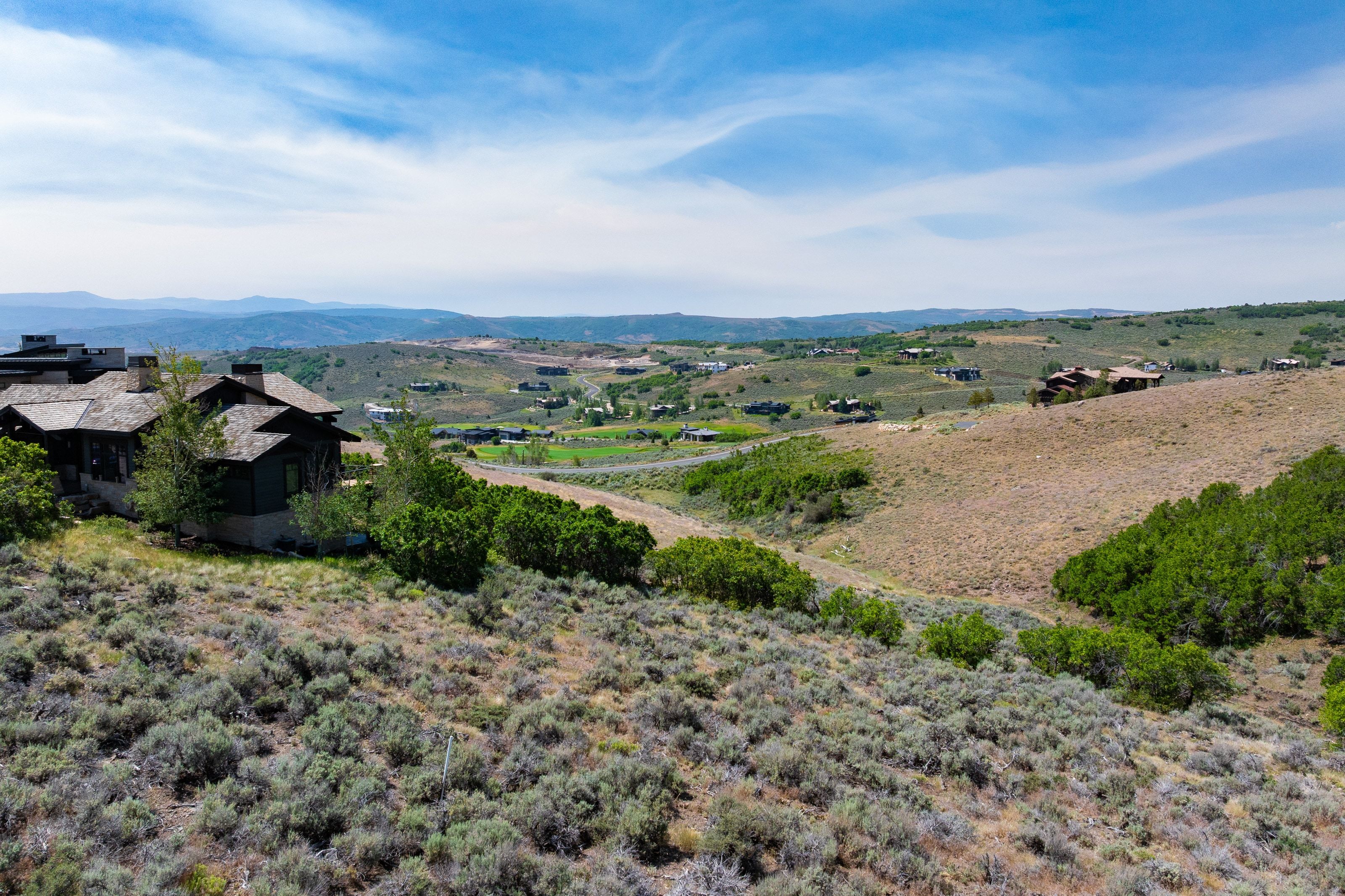 Sloped terrain featuring natural vegetation and distant hills