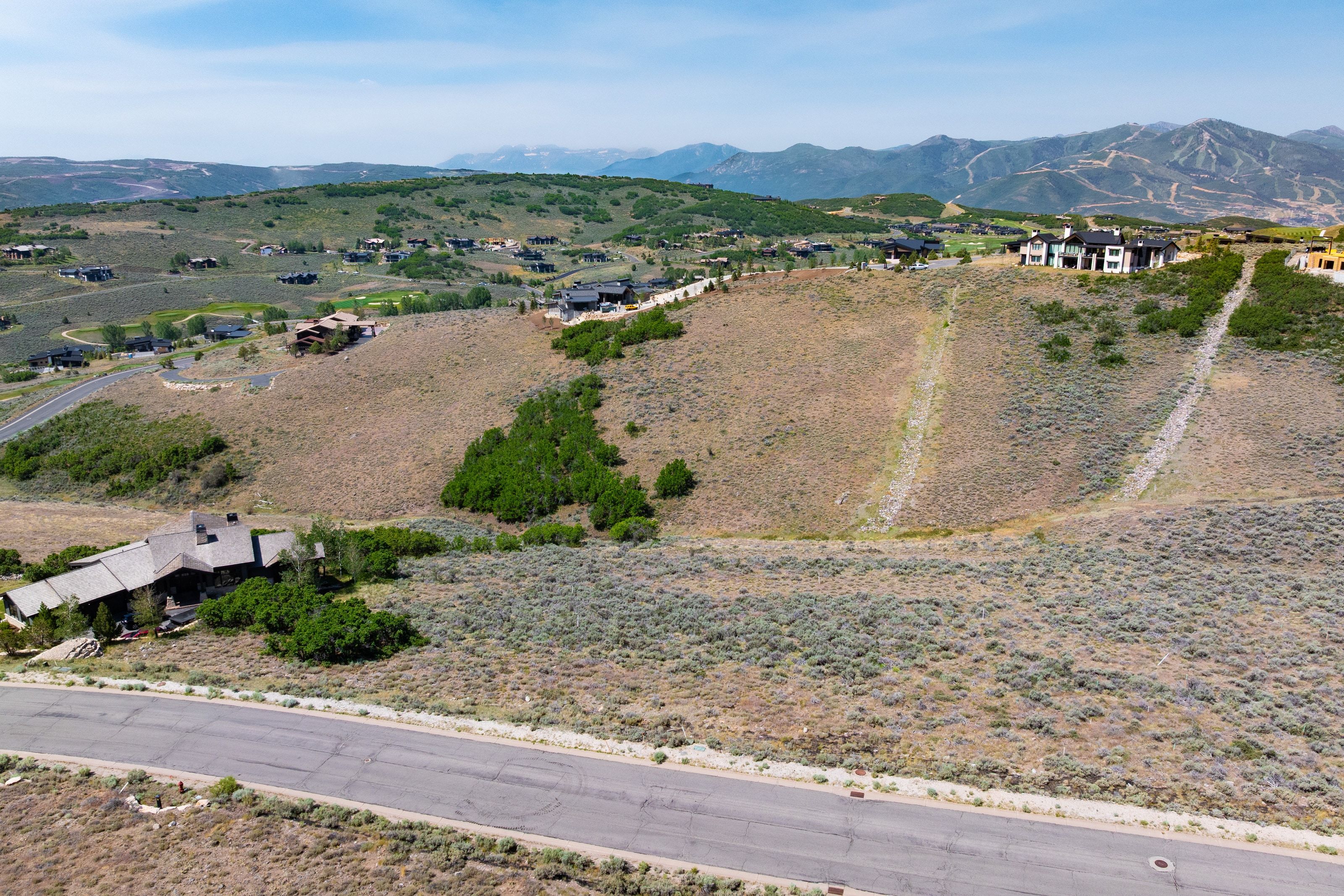 Expansive undeveloped land parcel featuring a paved roadway frontage
