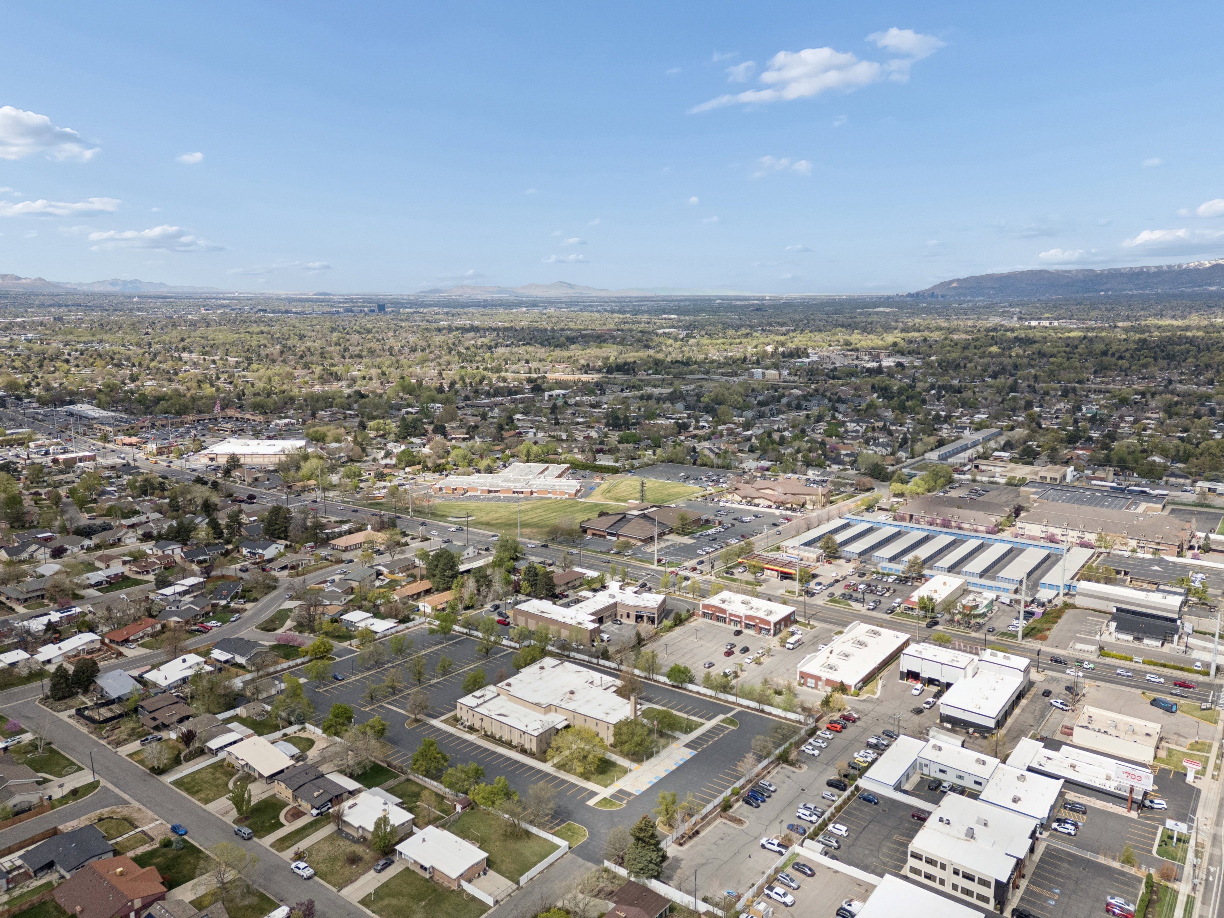 Expansive aerial perspective showcasing the property nestled in a mixed-use neighborhood with residential and commercial properties.