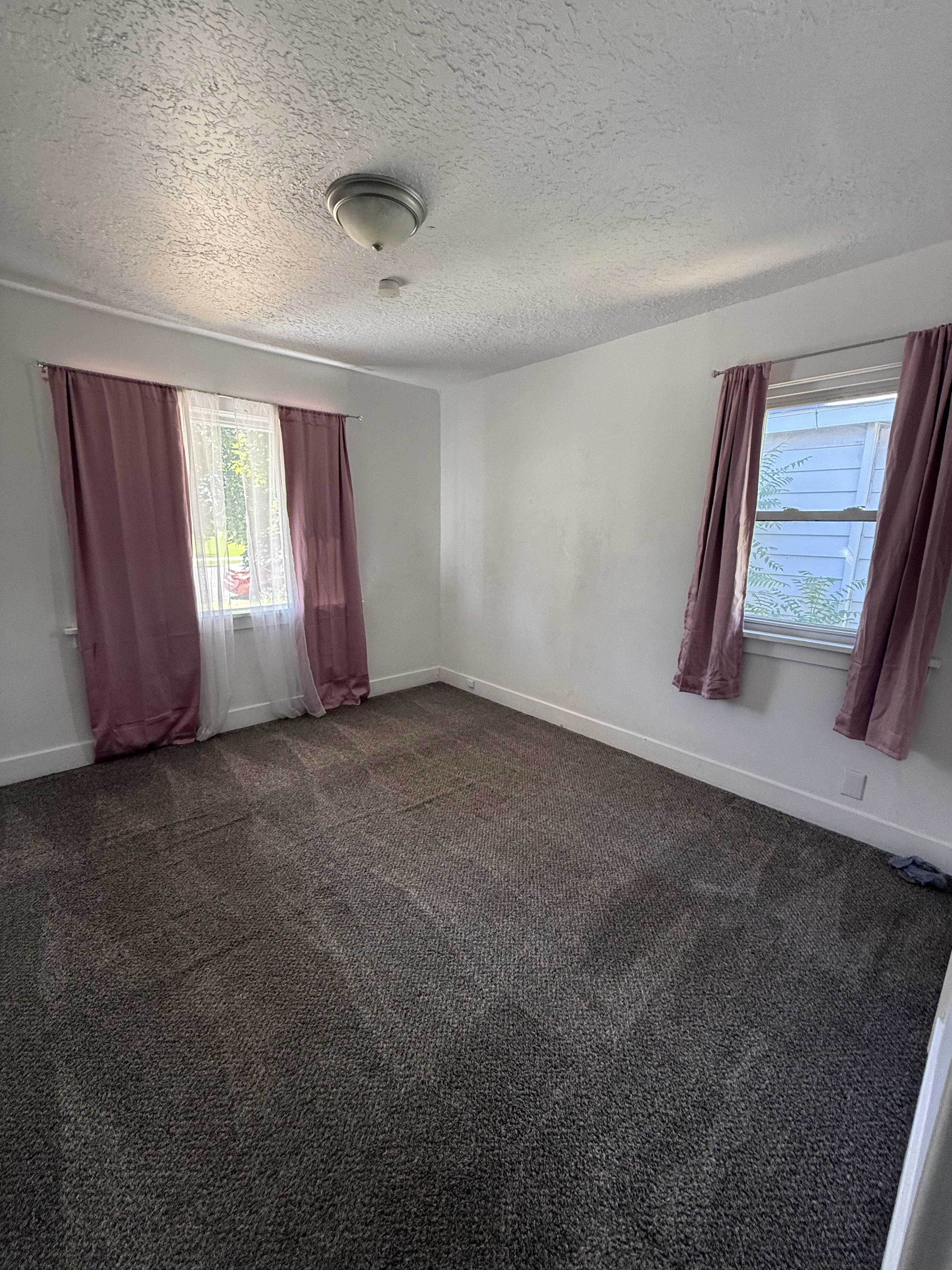 Carpeted room with a textured ceiling and two windows