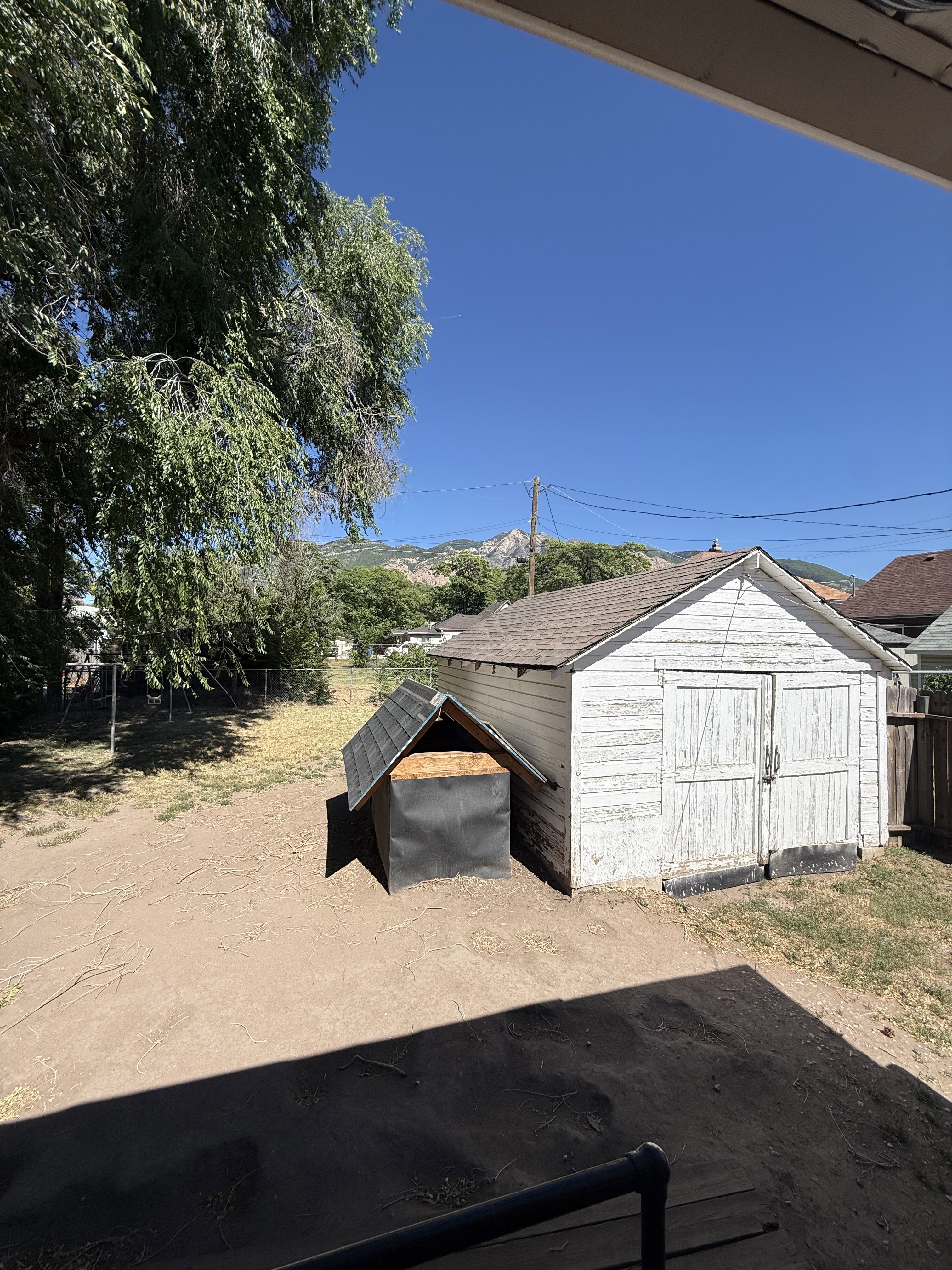 Outdoor storage shed with double doors, wood siding, and shingle roof