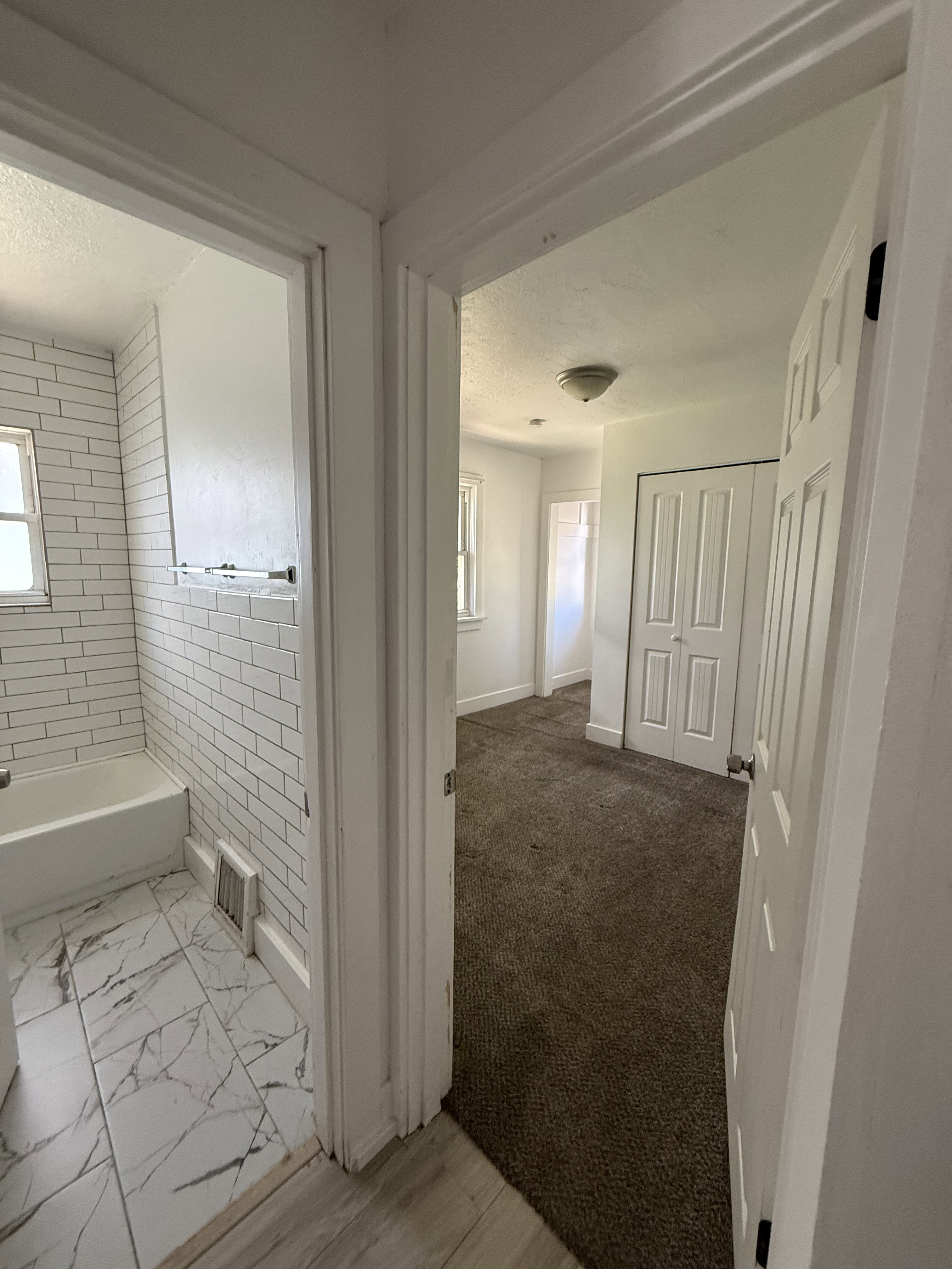 Bathroom featuring subway tile shower surround and marble-look floor tiles