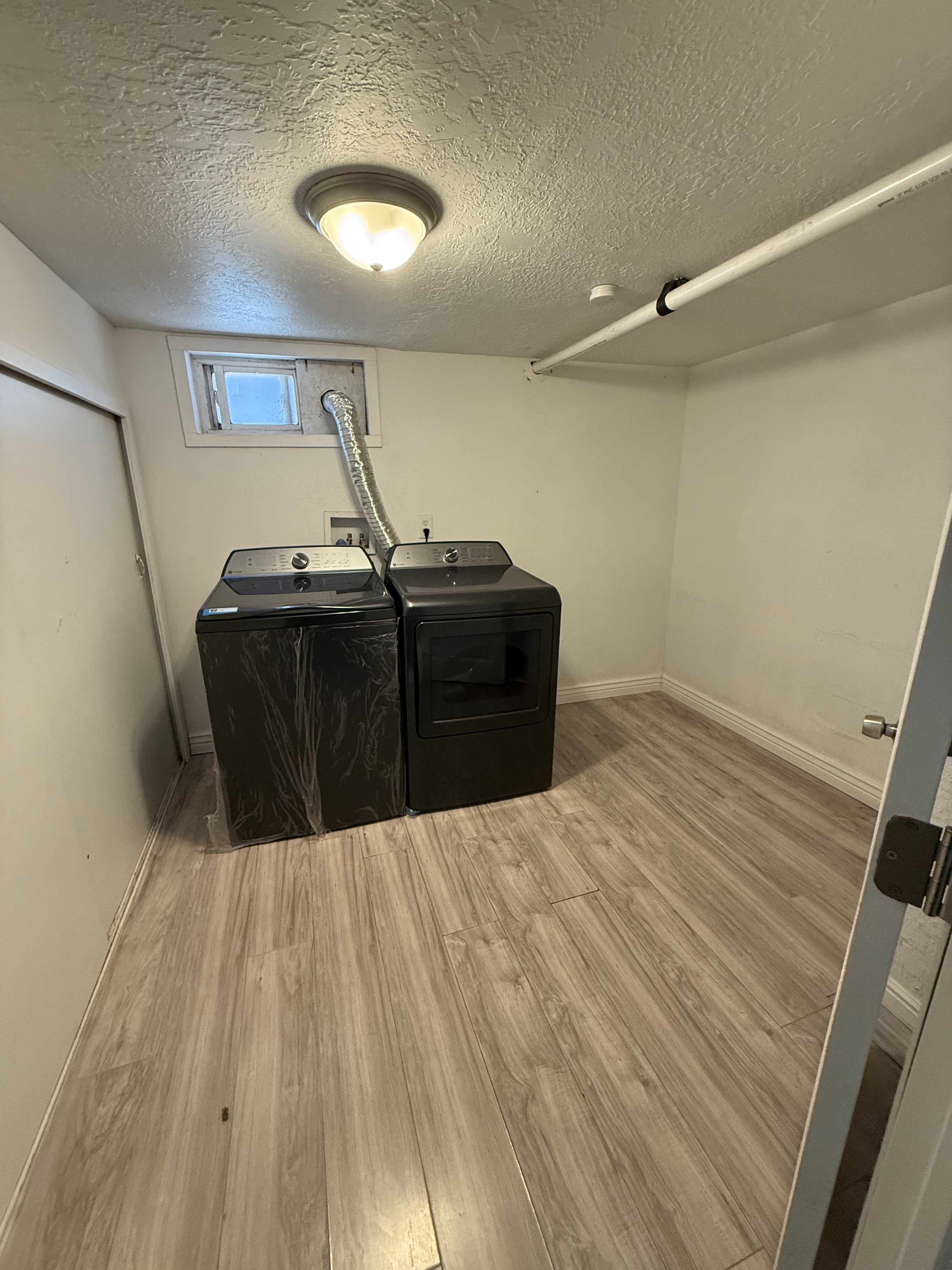 Utility area featuring wood-finish flooring, a flush-mount ceiling light, and a compact window