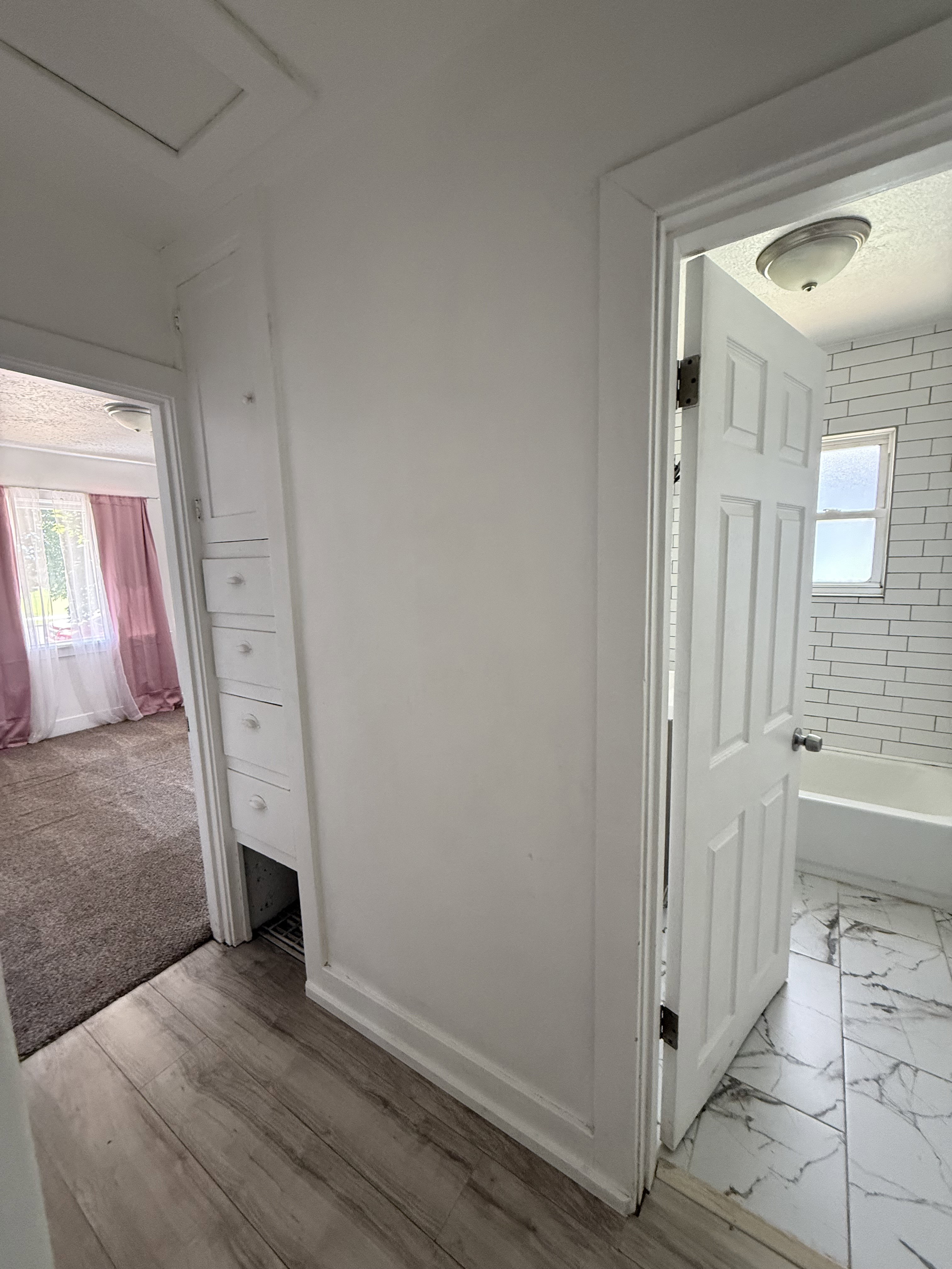 Hallway featuring wood-finish flooring, built-in cabinetry, and white paneled doors