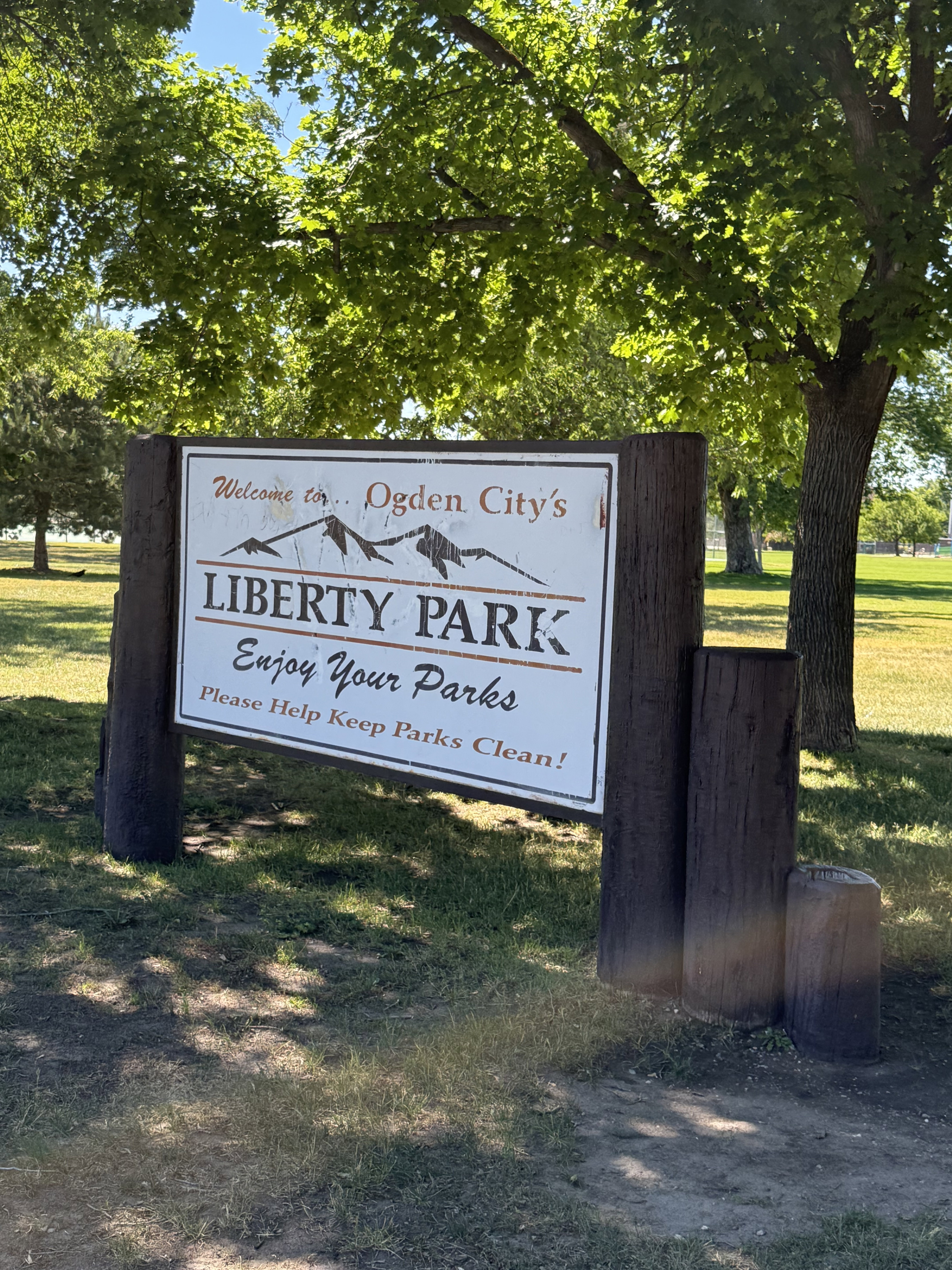 Wood-framed park signage featuring a white display board with "Ogden City's Liberty Park" text