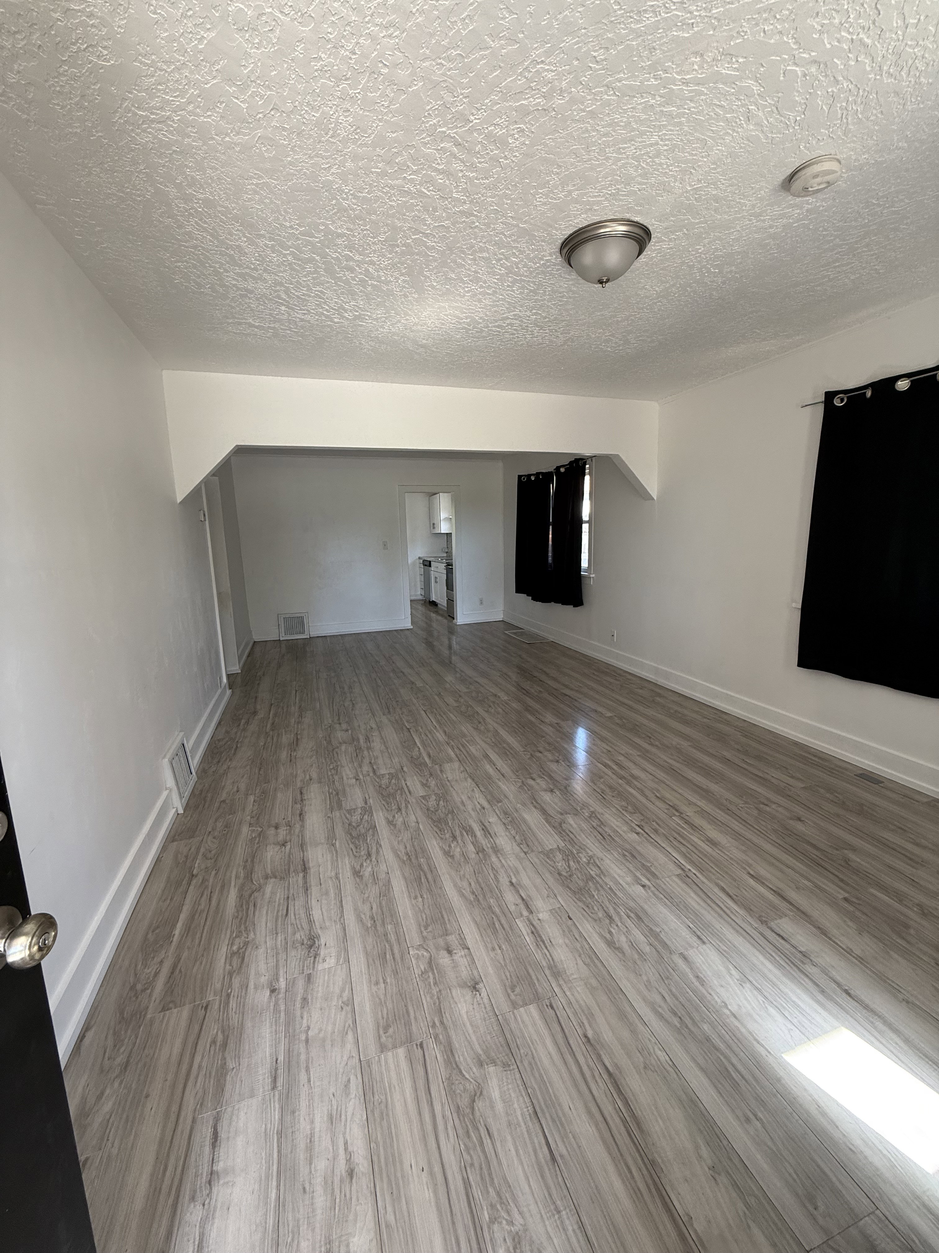 Open-concept living area featuring wood-finish flooring, white painted walls, and a semi-flush mount ceiling light
