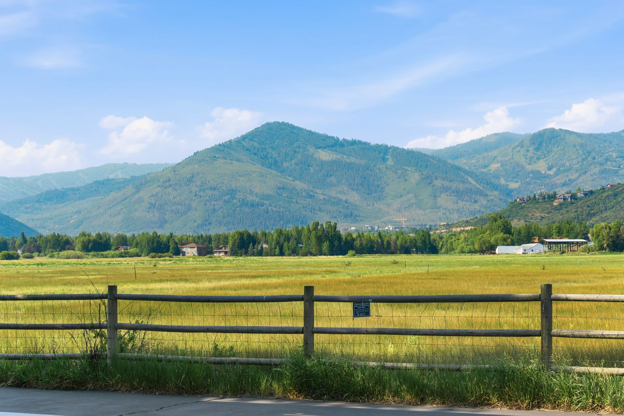 Extensive open field with distant mountain ranges and scattered residential structures