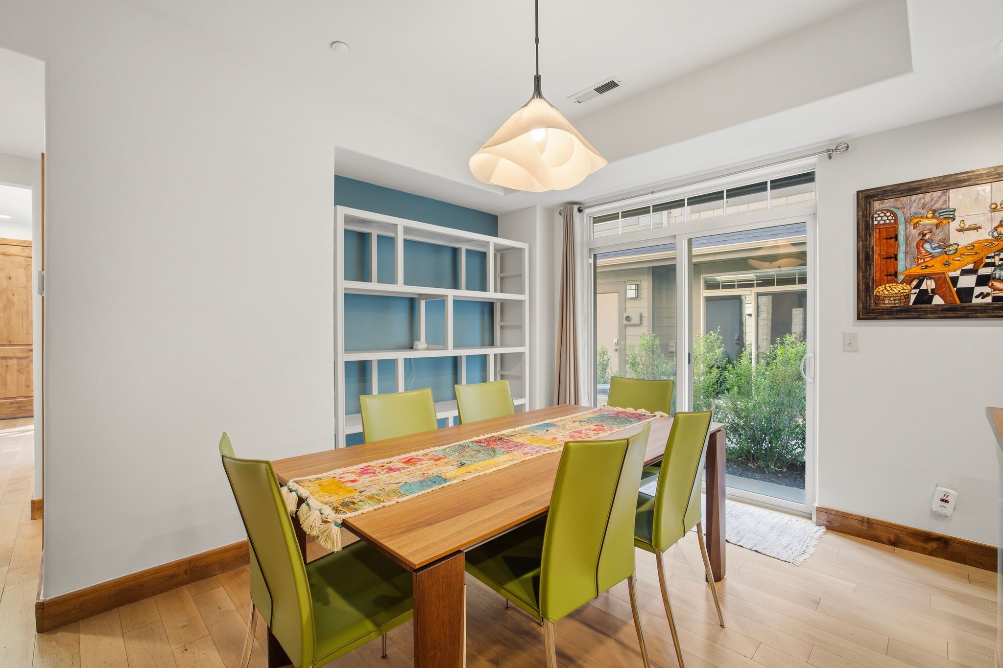Dining area featuring light wood-finish flooring and a contemporary pendant light fixture