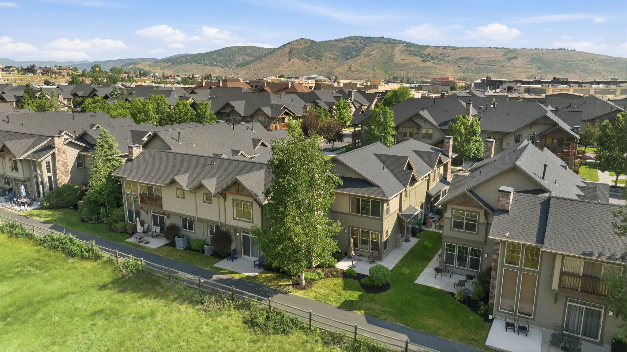 Residential community featuring multi-story properties with dark shingle roofs, balconies, and ground-level patios