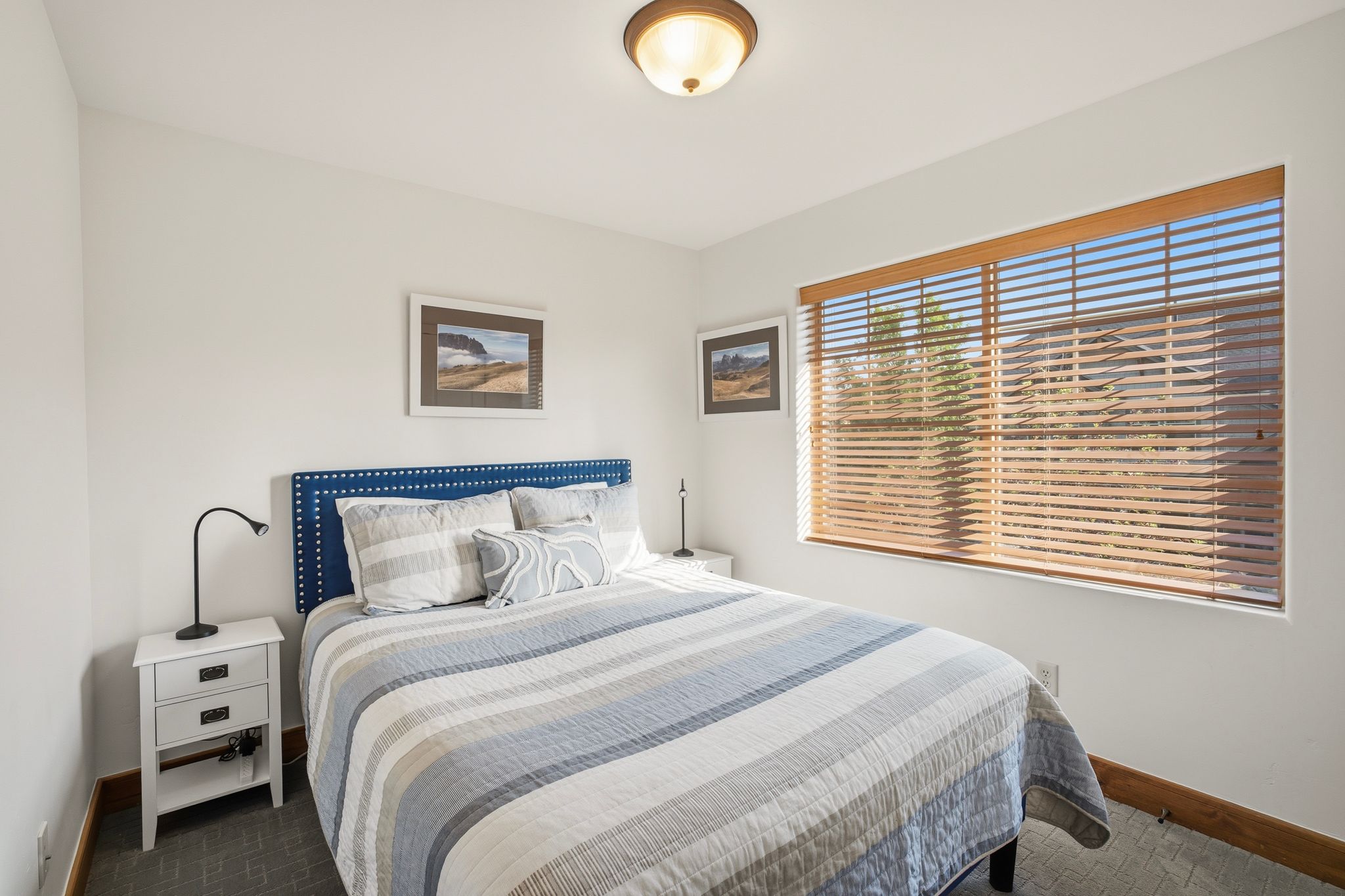 Bedroom featuring white walls, wood-finish window blinds, and a semi-flush mount ceiling light fixture
