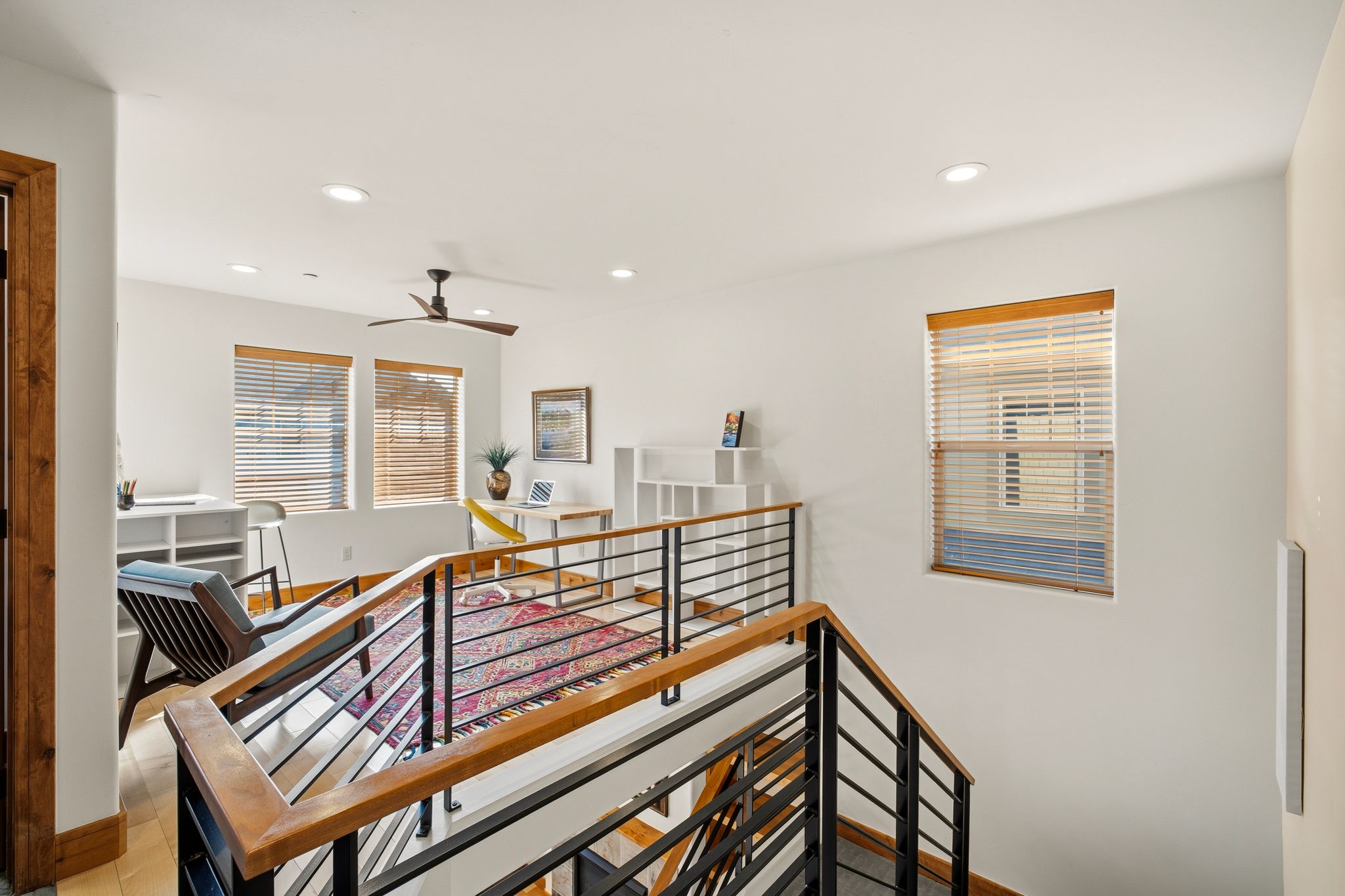 Upper-level landing featuring a contemporary railing with wood-finish handrails and black metal balusters