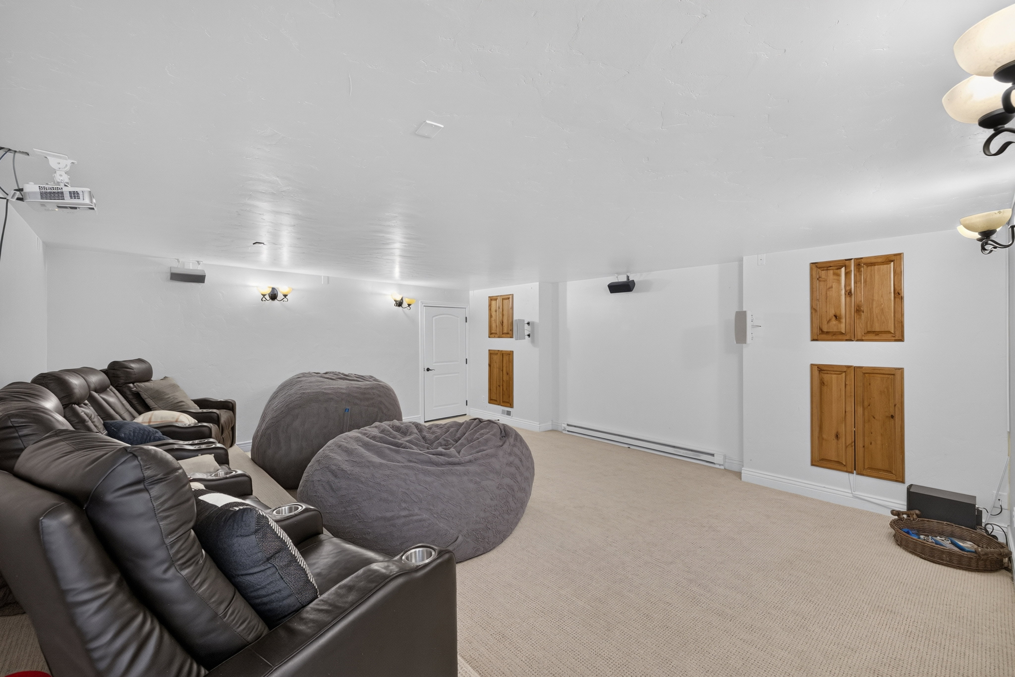 Spacious entertainment room featuring light-toned carpeting, recessed lighting, and wall-mounted sconces
