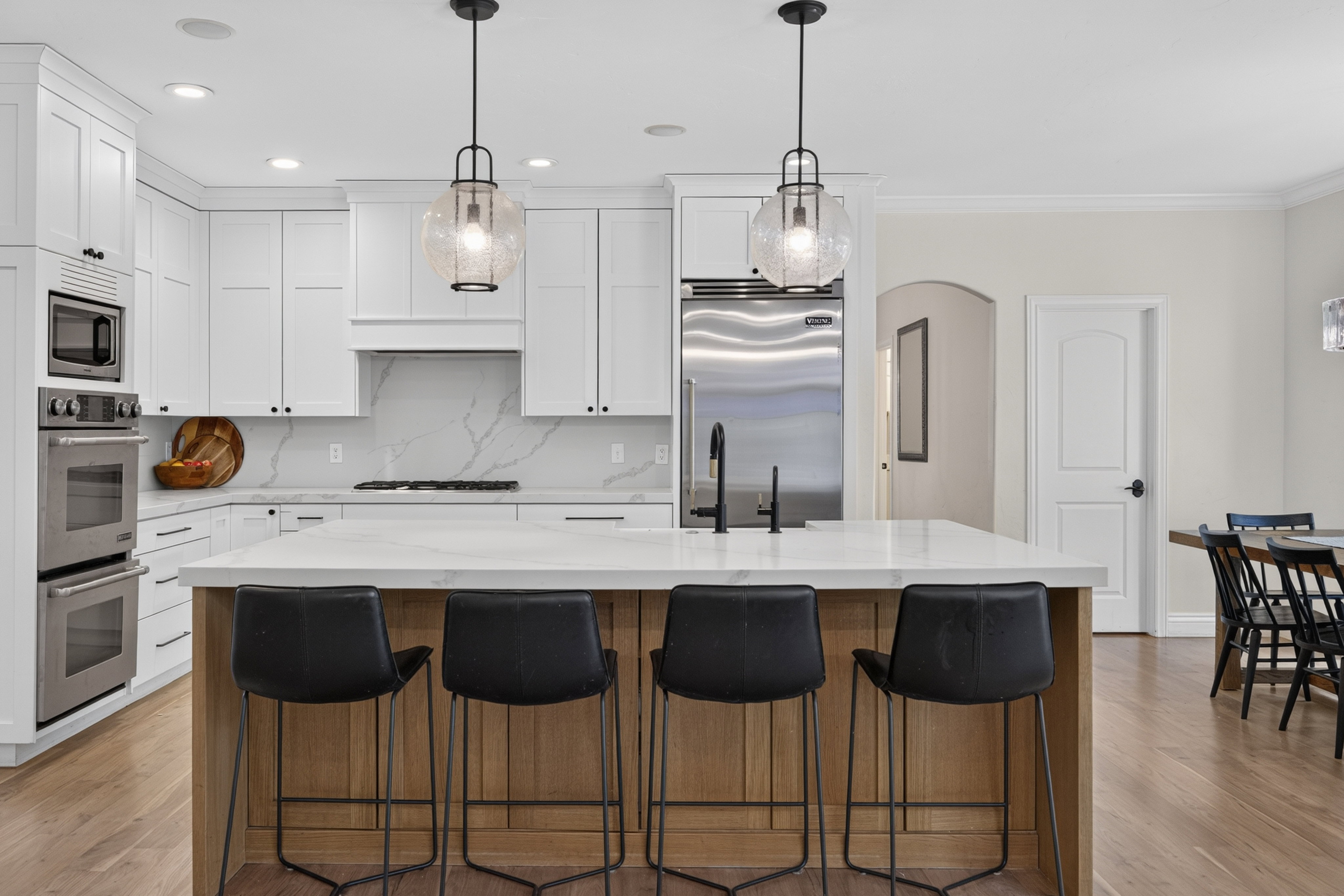 Modern kitchen with a substantial central island, white shaker cabinetry, and a full suite of stainless steel appliances