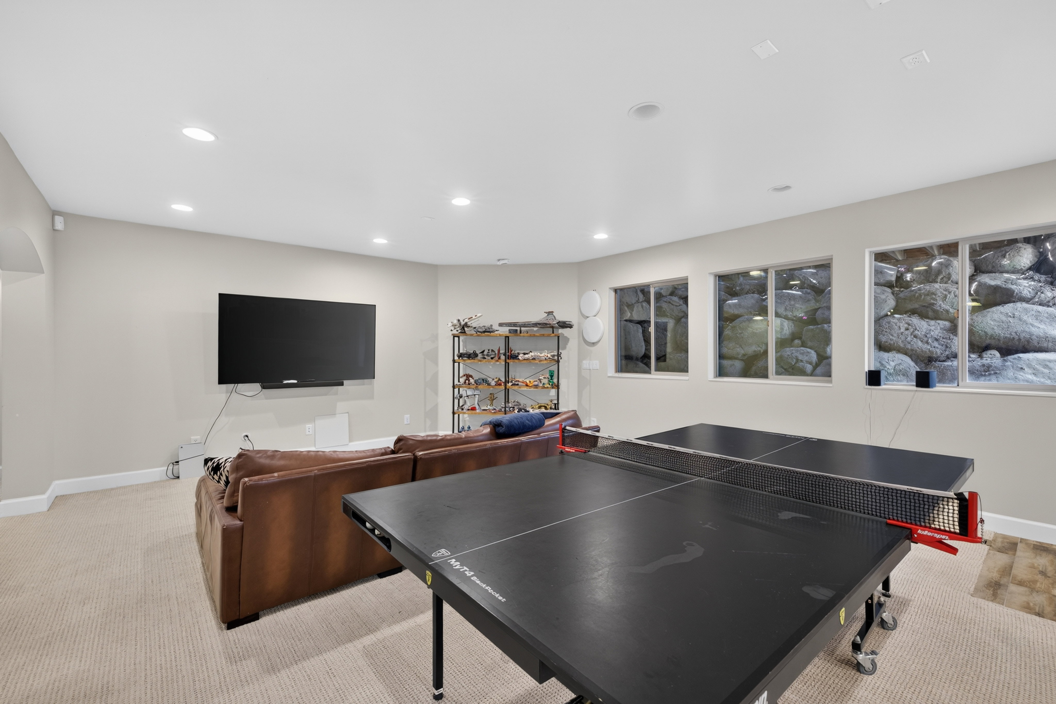 Recessed lighting illuminates this versatile space, featuring neutral carpeting and light-toned walls