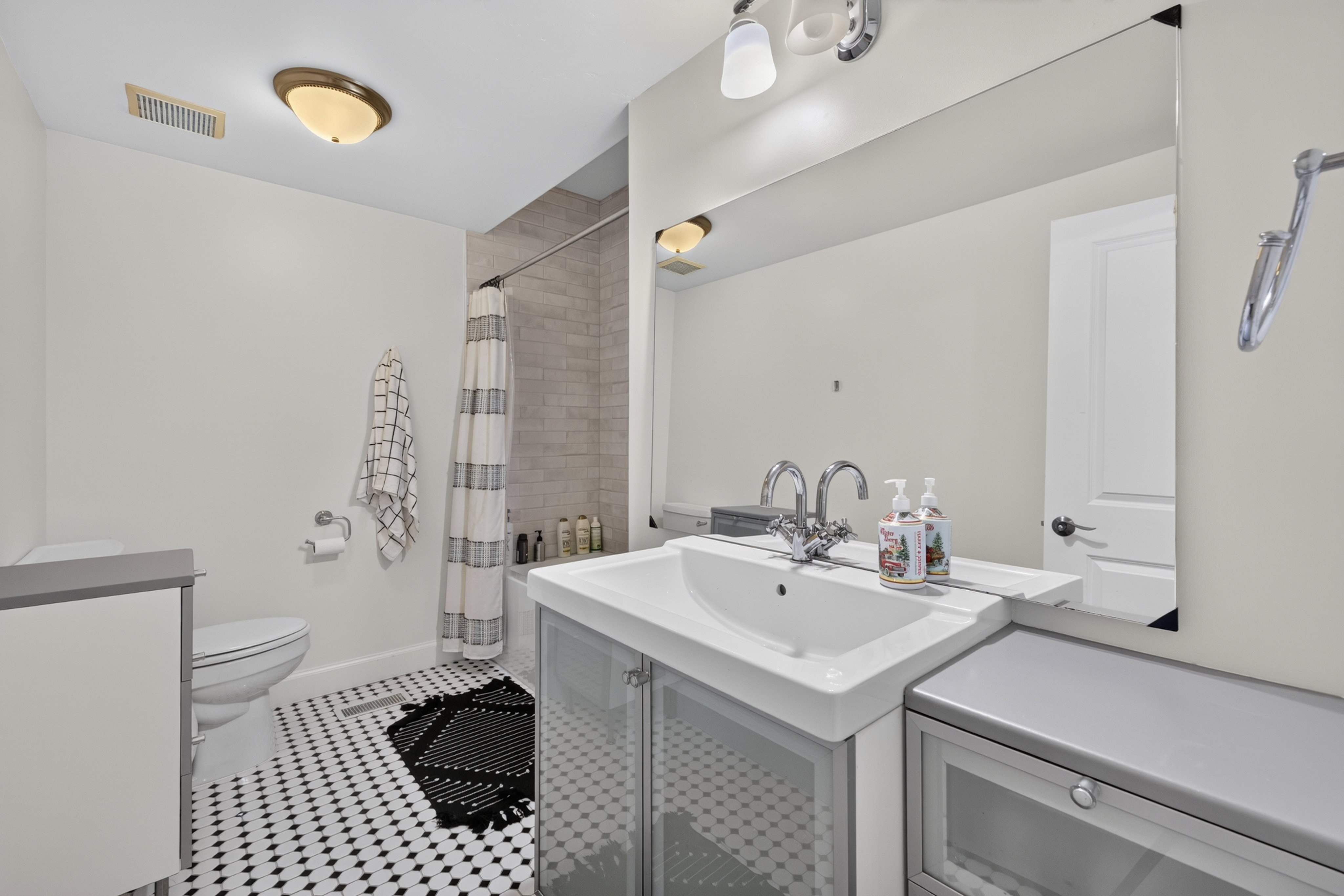 Bathroom featuring a white vanity with integrated sink, chrome fixtures, and a large wall-mounted mirror
