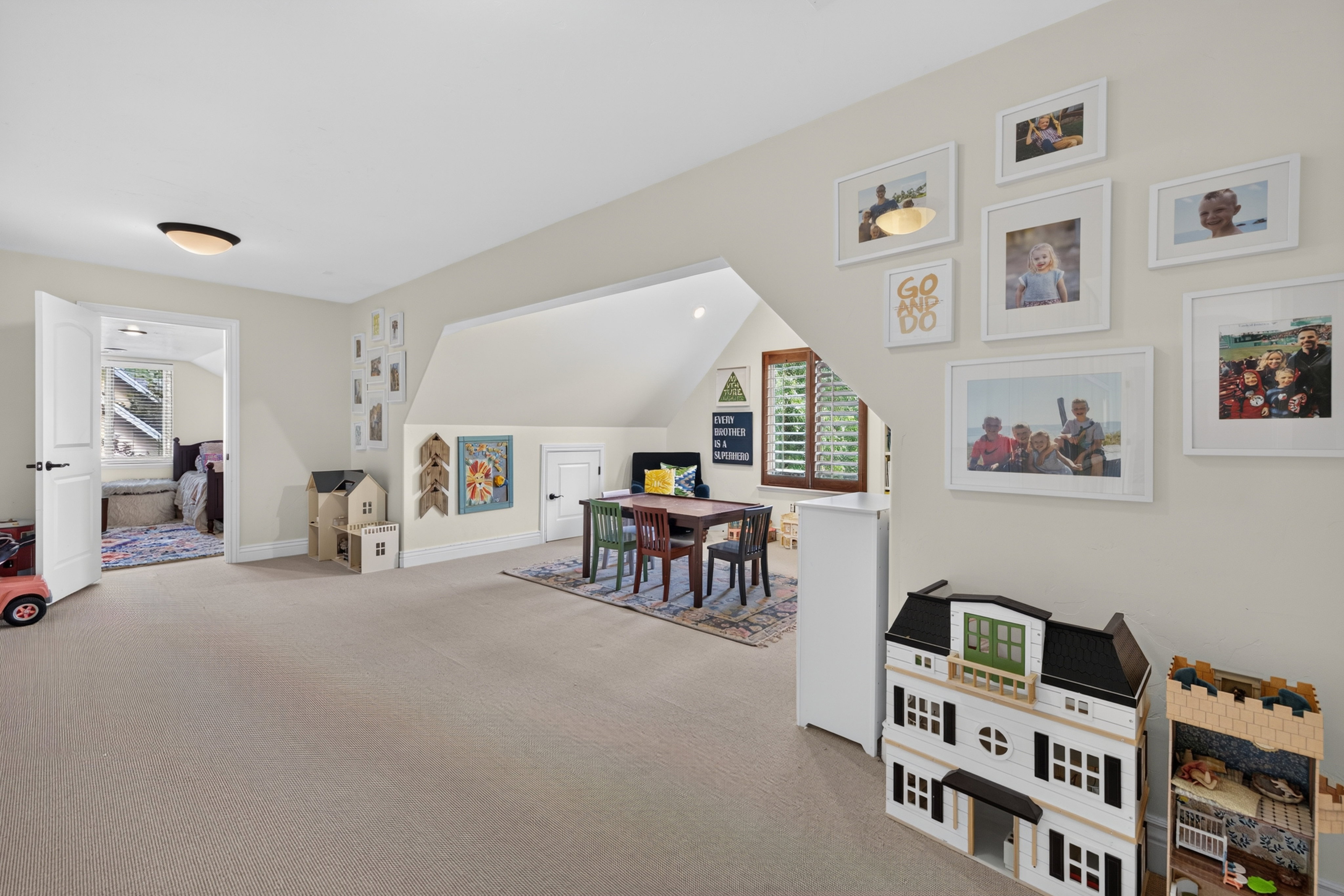 Spacious carpeted room featuring a sloped ceiling, recessed lighting, and a white paneled door