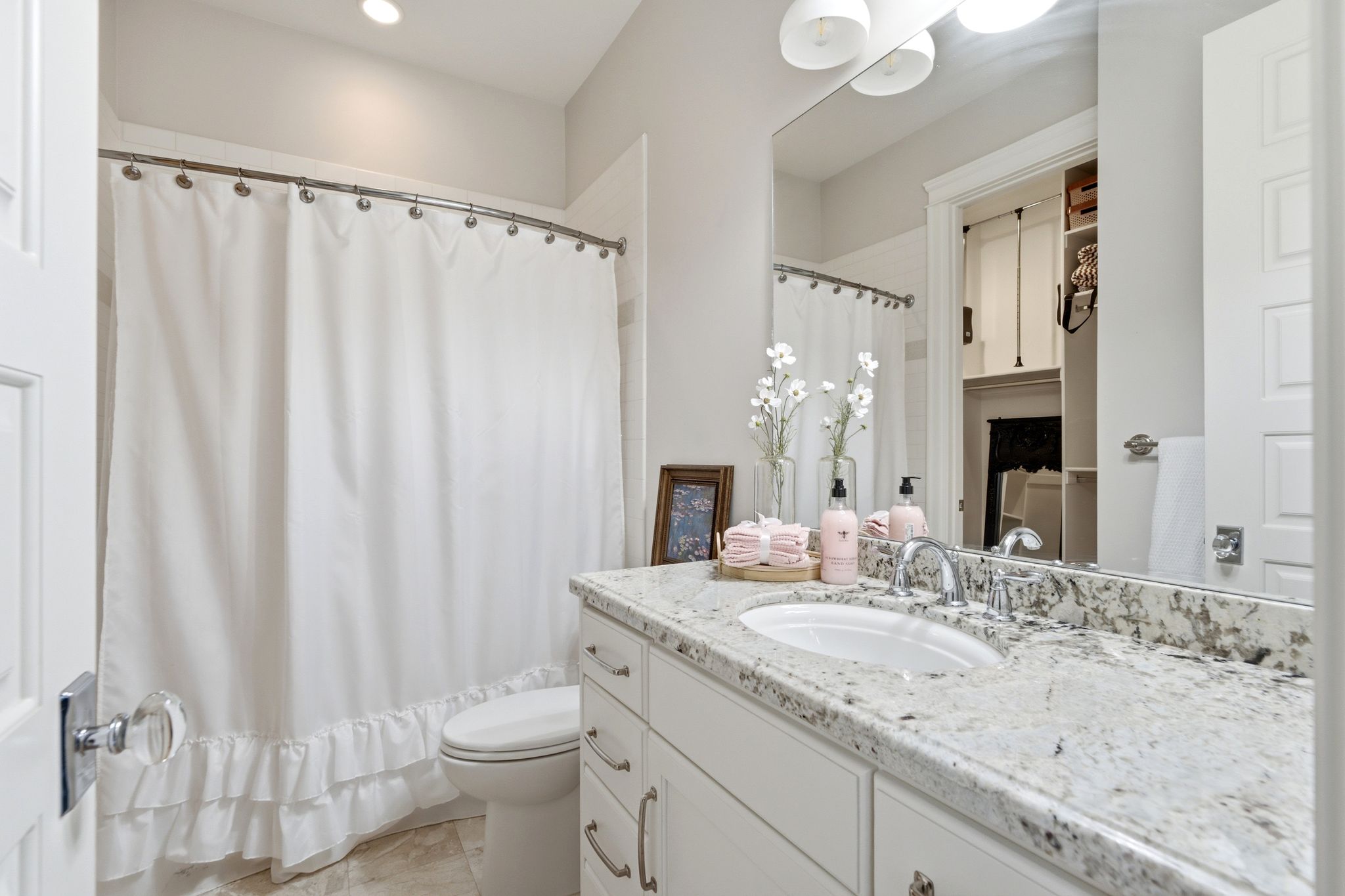Bathroom featuring a white vanity with silver hardware, a speckled light-toned countertop, and a built-in sink with a chrome faucet
