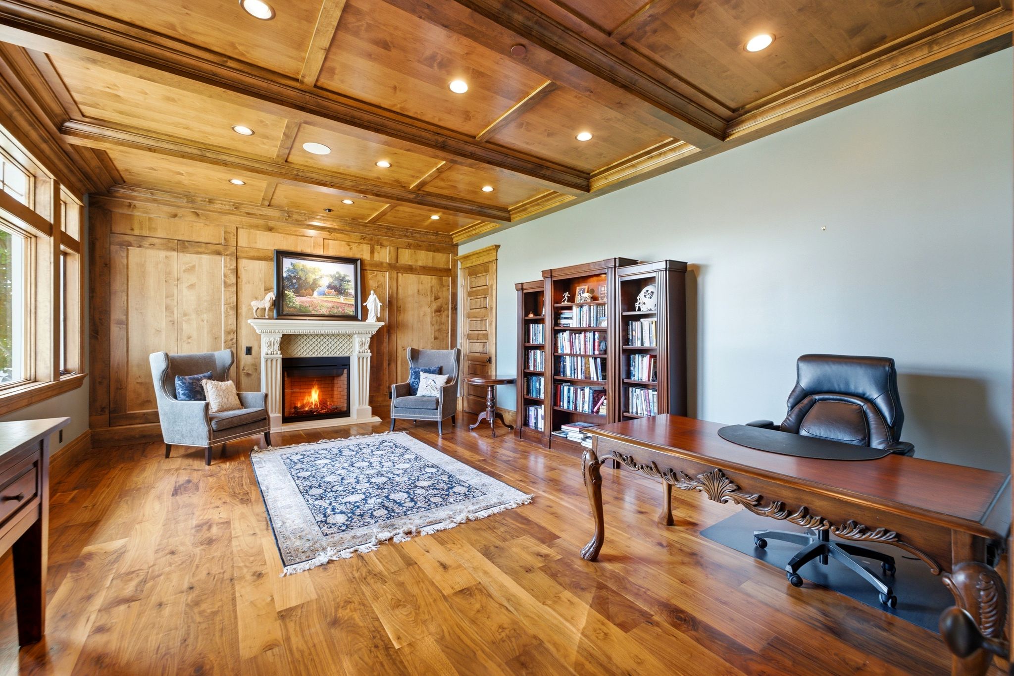 Wood-paneled room featuring wood-finish flooring, a stone fireplace, recessed lighting, and built-in shelving