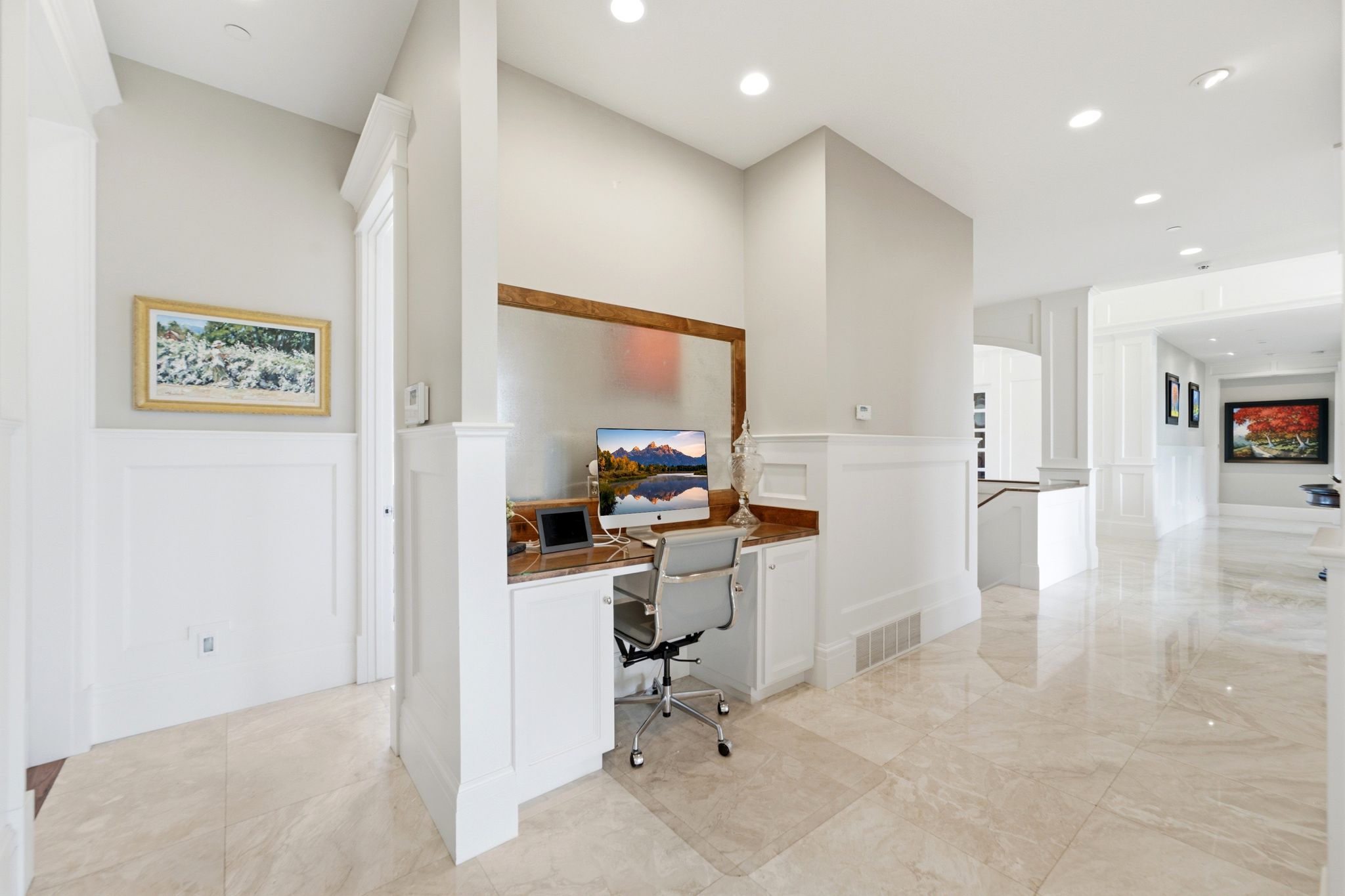 Integrated desk area with a wood-finish countertop, built-in cabinetry, and wainscoting