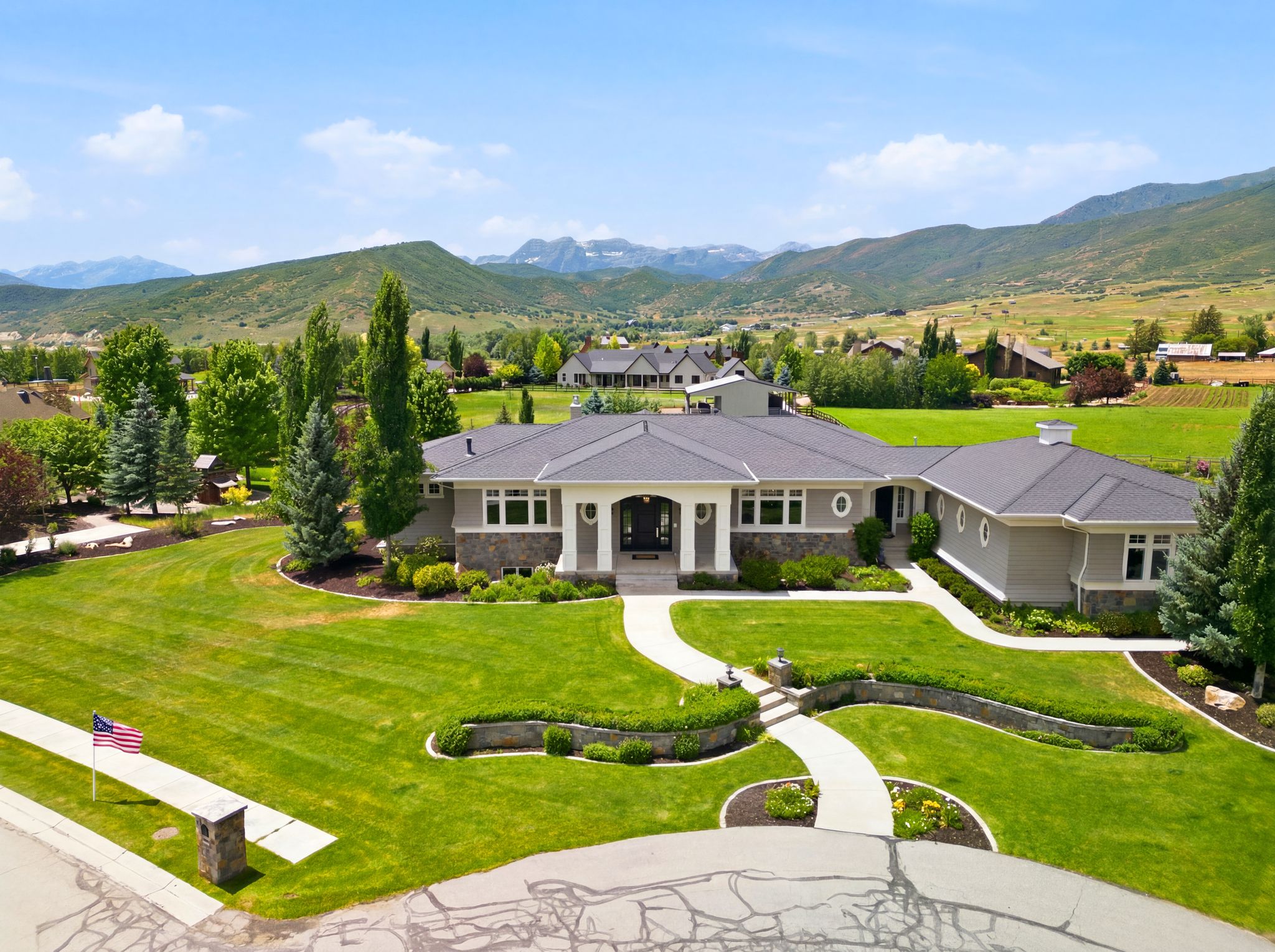 Spacious residence featuring a multi-gabled roofline, light gray siding, and stone accents