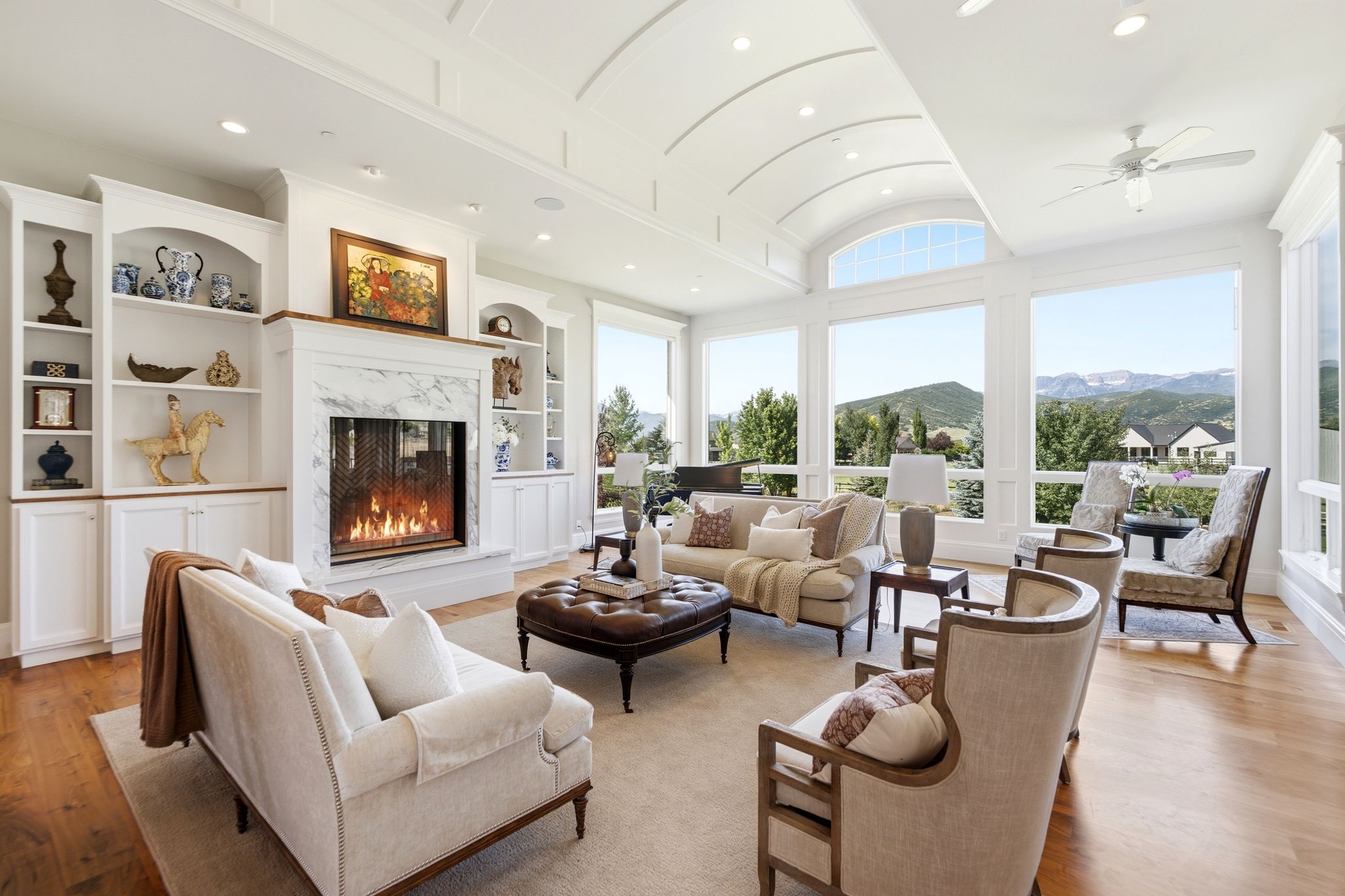 Vaulted ceiling featuring a central arch and recessed lighting, accompanied by a gas fireplace with a marble surround and hearth