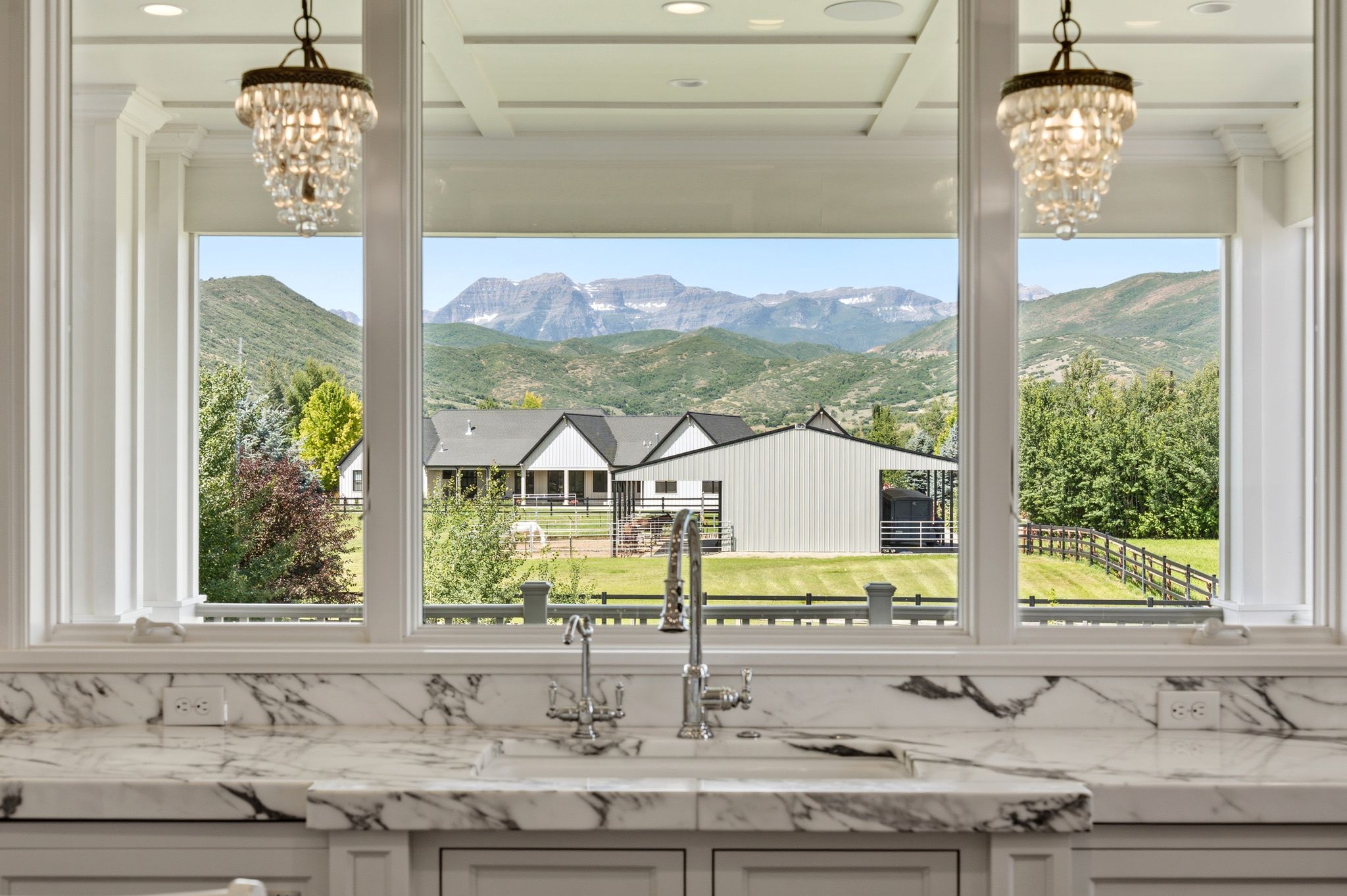 Gourmet kitchen with a large window overlooking a landscaped property, mountains, and trees