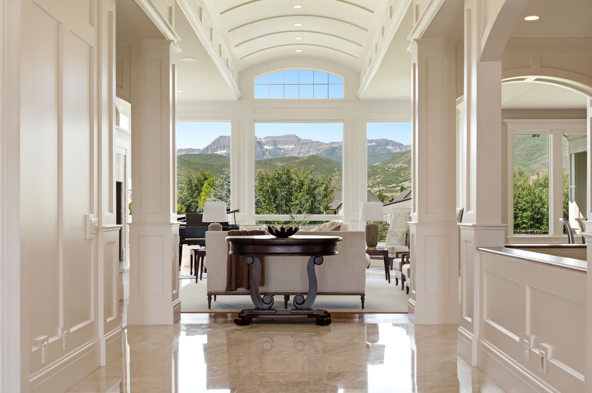 Grand entry hallway featuring polished stone flooring, intricate wainscoting, and an arched tray ceiling